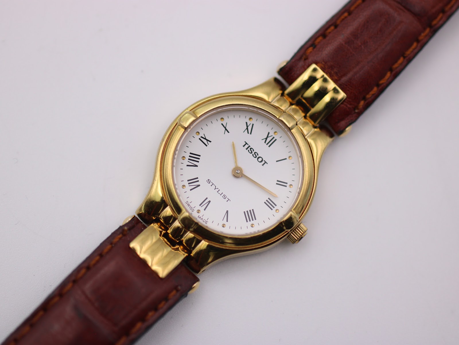 Overhead close-up of the Tissot Stylist dial, showing Roman numerals and "SWISS MADE" text.