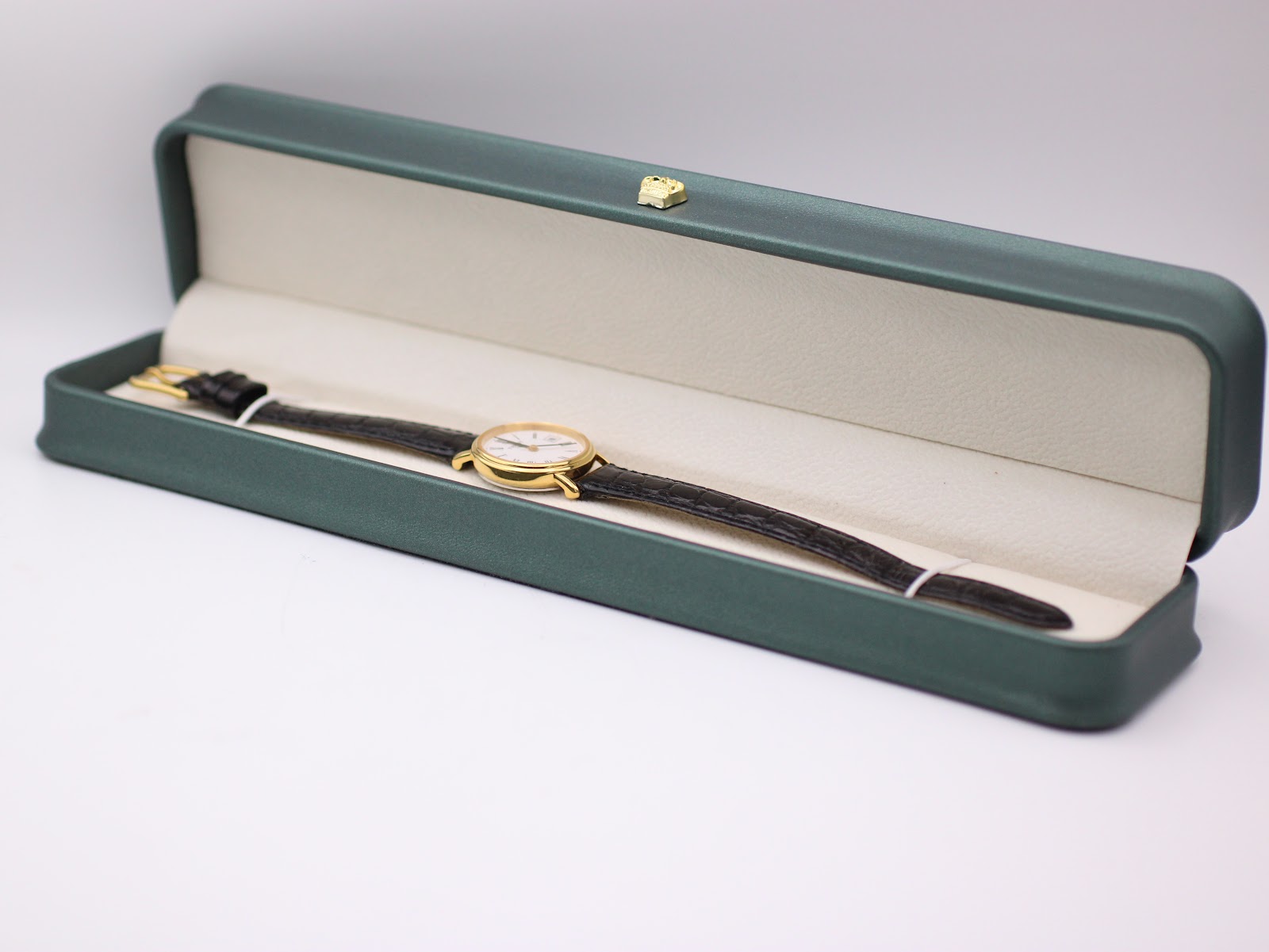 The Tissot watch resting inside a generic green leatherette presentation display box.