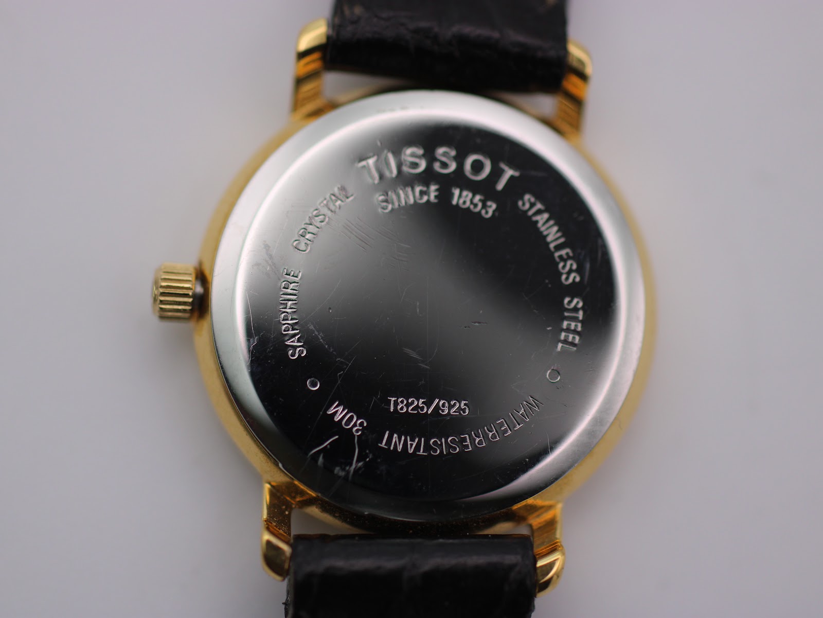 Close-up of the stainless steel case back of the Tissot T825/925, showing "TISSOT", "SAPPHIRE CRYSTAL", "STAINLESS STEEL", "30M WATERRESISTANT" and model number.