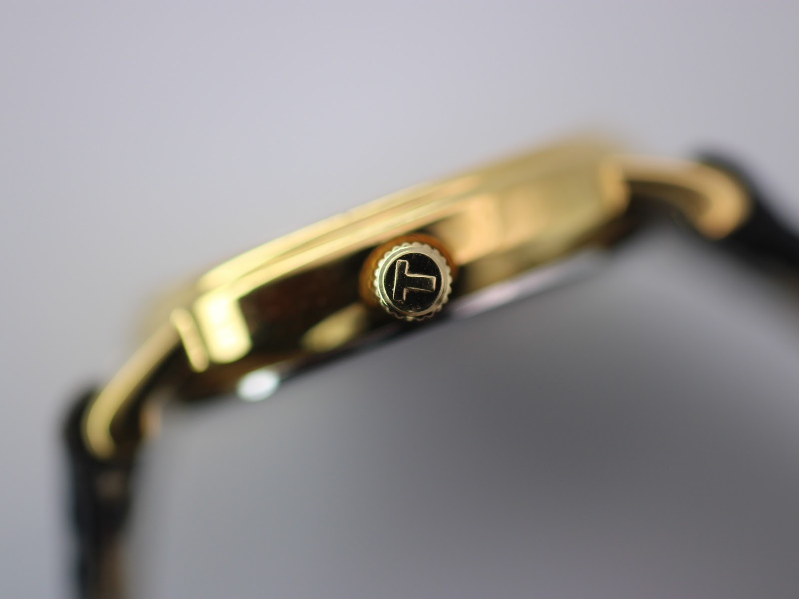Detailed side view of the gold-toned watch case and the signed Tissot crown with its distinctive 'T' logo.