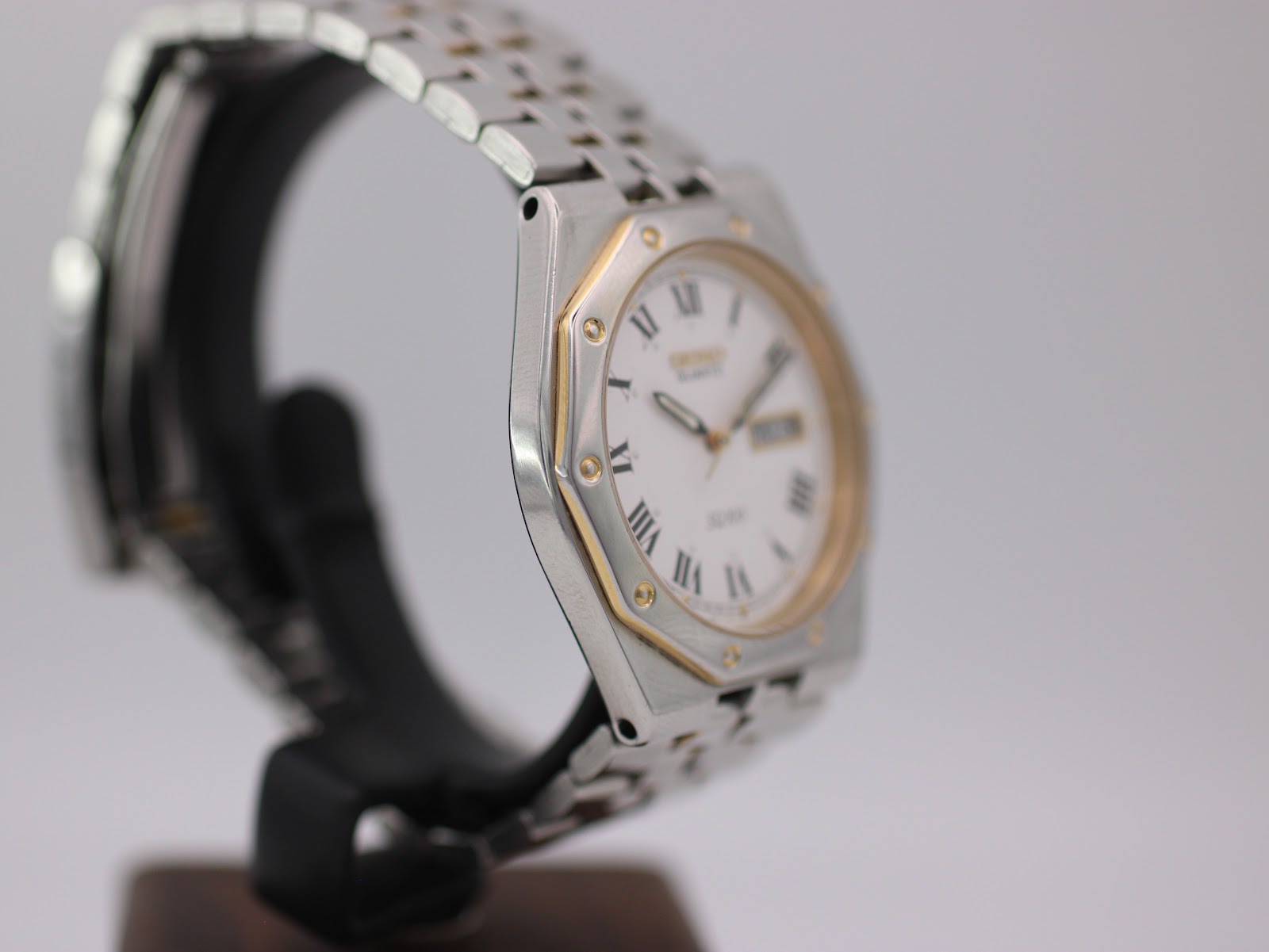 Angled side view of the Seiko SQ 100 highlighting the two-tone case and multi-link bracelet.