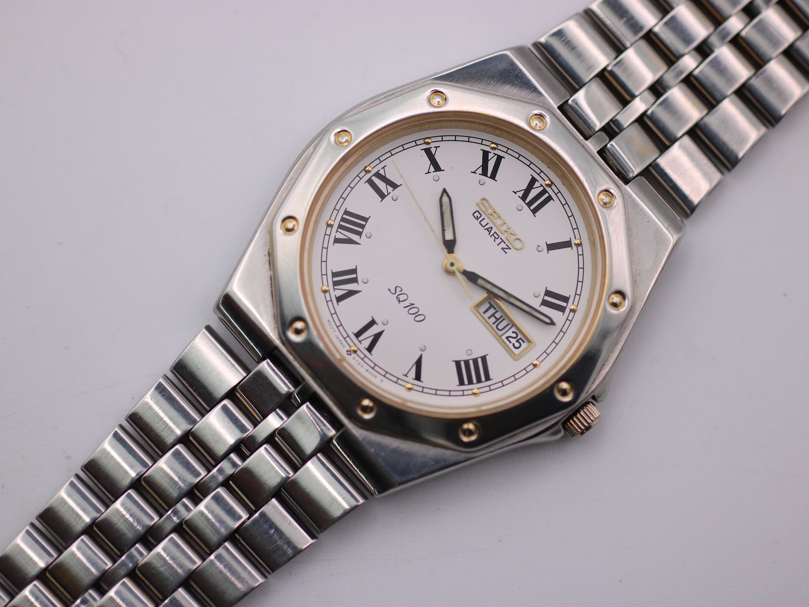 Overhead flat lay shot of the Seiko SQ 100 two-tone watch with its steel bracelet extended.
