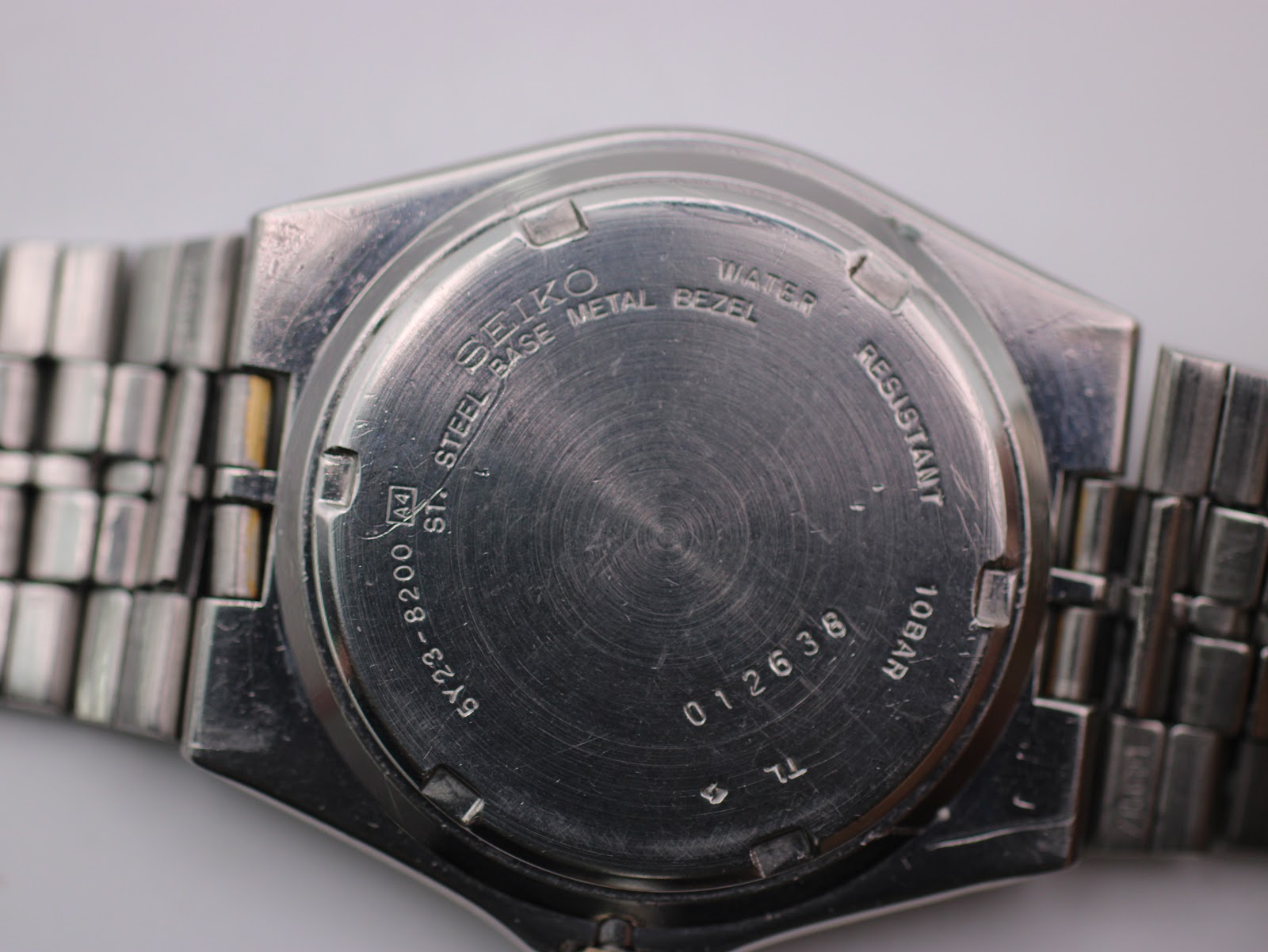 Close-up of the Seiko SQ 100 case back displaying model numbers, serial number, and '10BAR WATER RESISTANT' engraving.