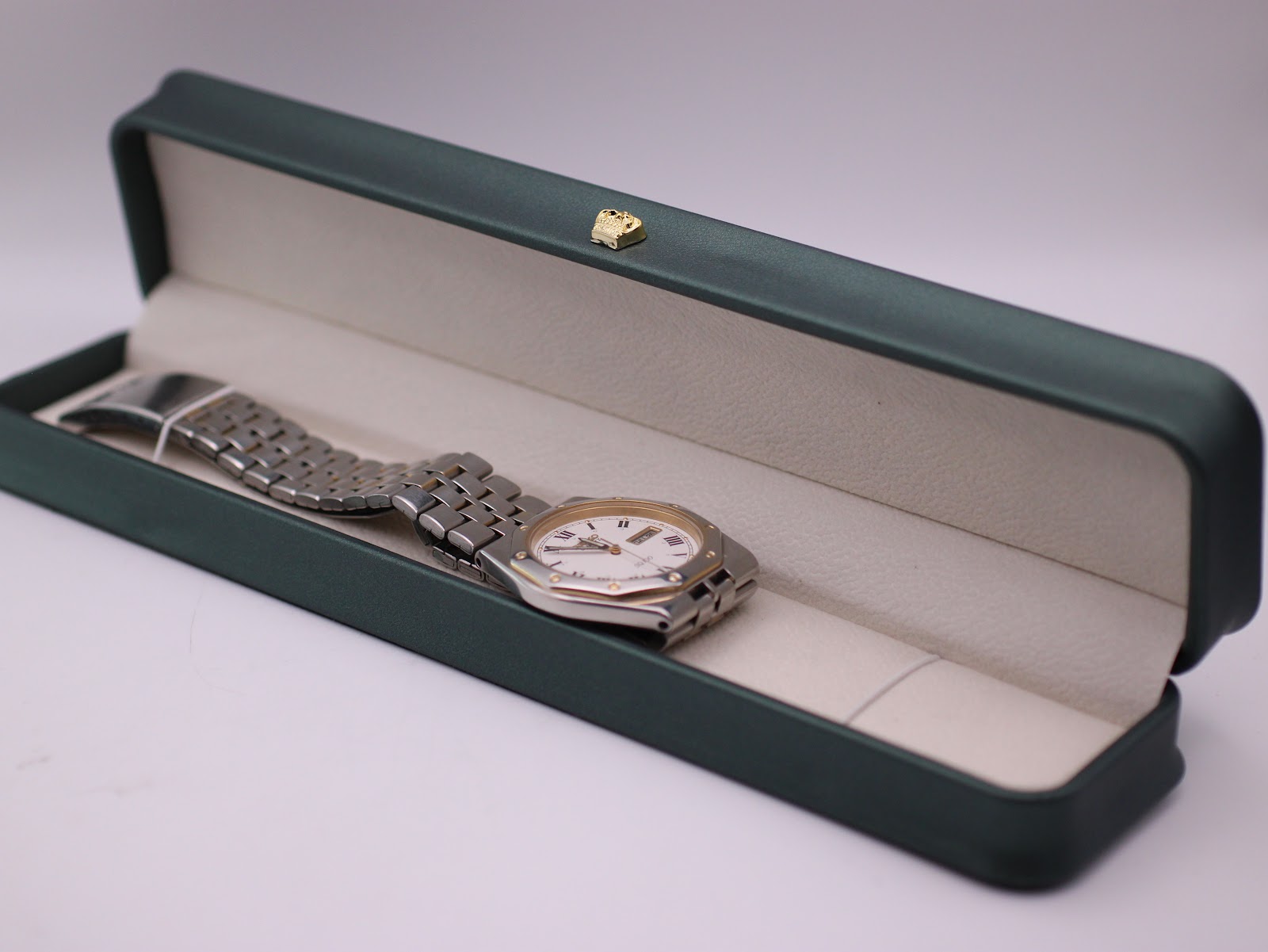 Seiko SQ 100 watch resting in a generic green leatherette presentation box.