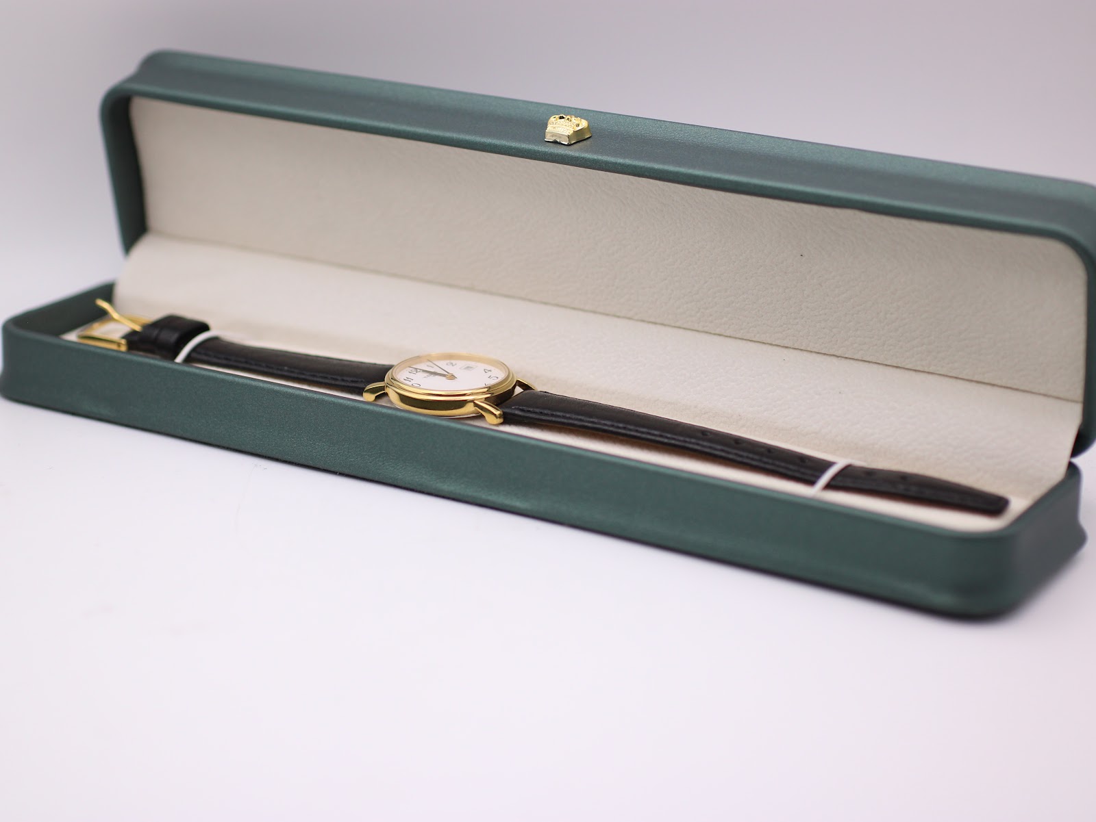 Tissot watch and strap lying in a green generic display box.
