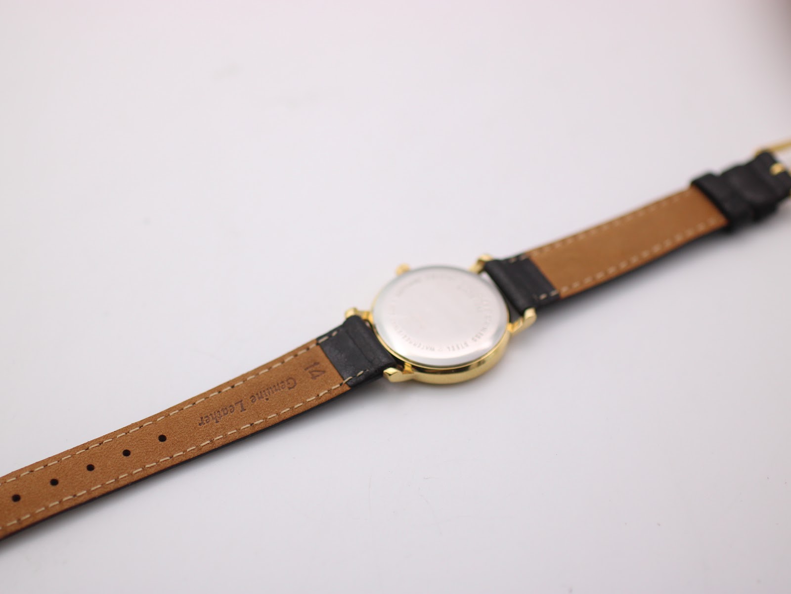 View of the watch from the back, showing the stainless steel case back and the underside of the black leather strap with "Genuine Leather" and "14" lug width marking.