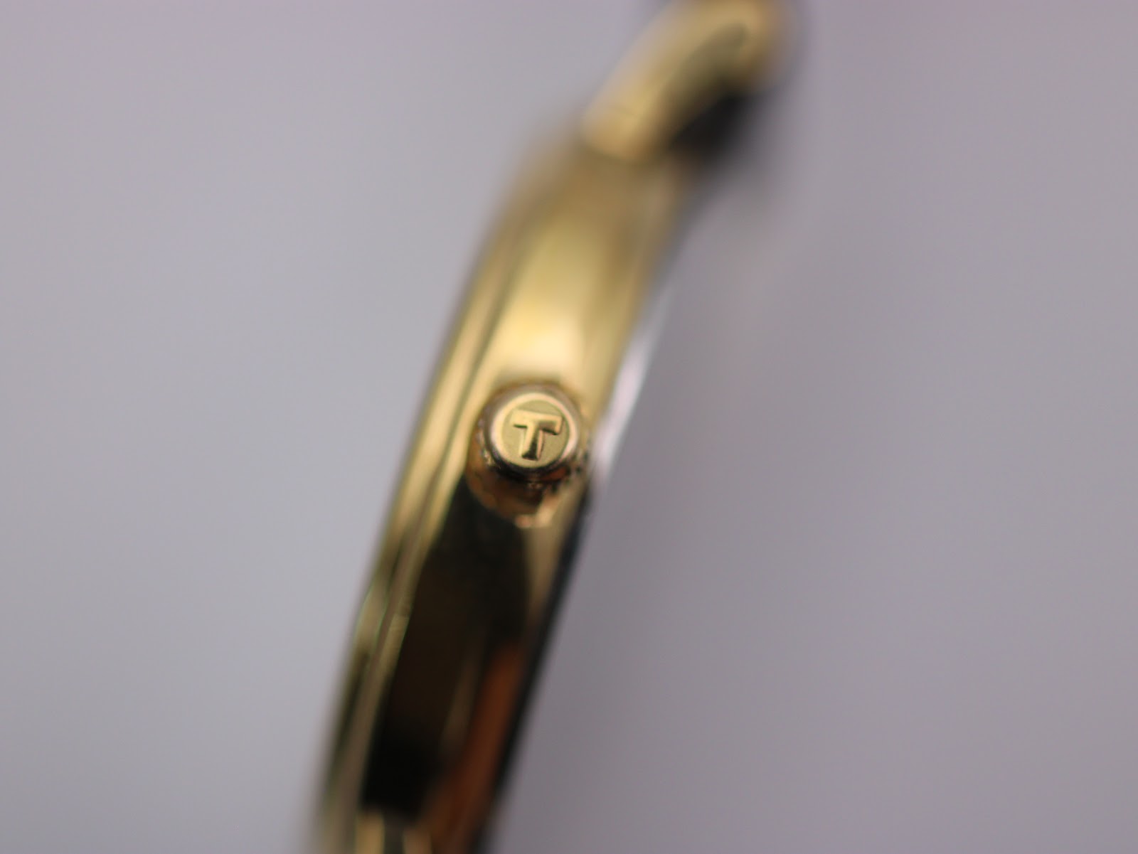 Close-up of the Tissot gold-toned crown with the Tissot 'T' emblem.