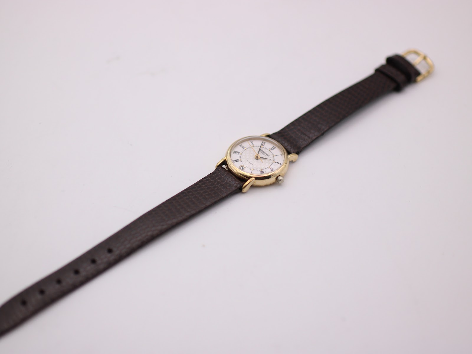 Overhead view of the watch with its full brown leather strap laid out flat.