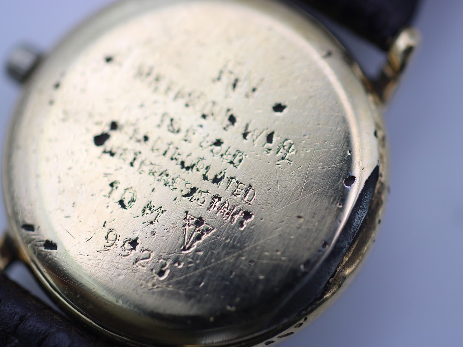 Macro shot of the heavily worn gold-plated case back, showing model 9923 and "10 M GOLD PLATED" engravings.
