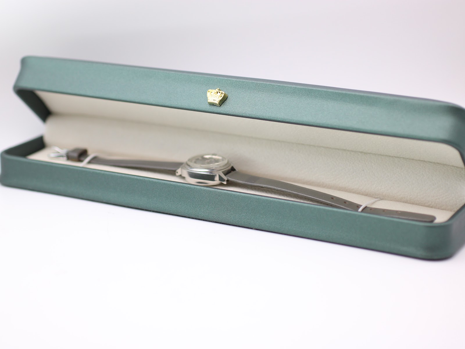 The Seiko 2205-0240-P watch with its grey leather strap resting inside a generic green leatherette display box.