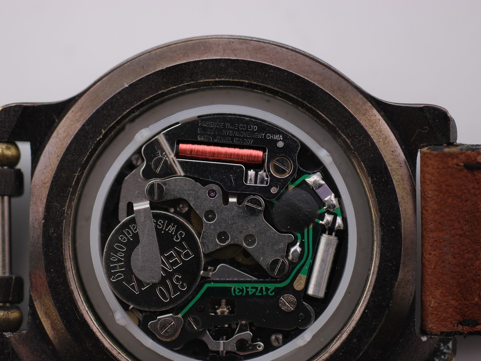 Extreme close-up view of the internal quartz movement with the battery visible, marked 'RENATA SWISS'.