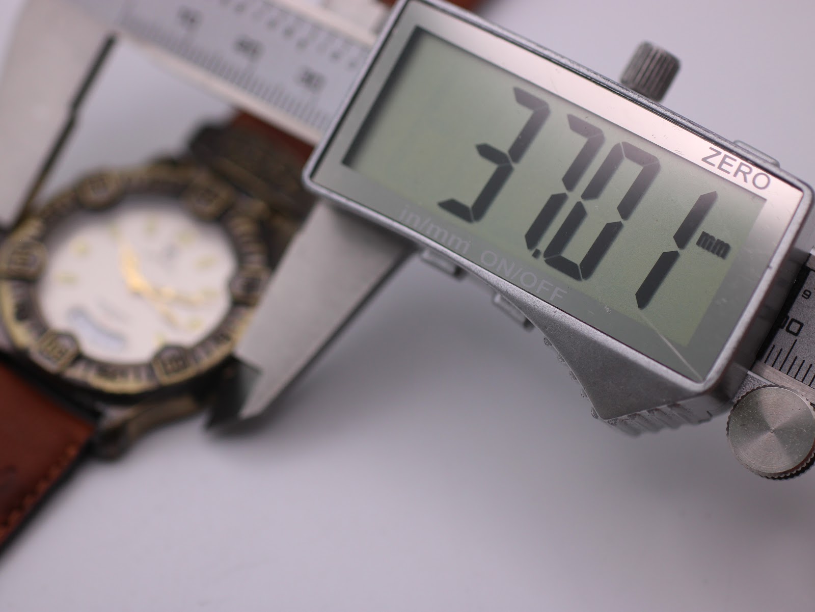 Digital caliper measuring the case diameter of the watch, displaying an exact measurement of 37.07mm.