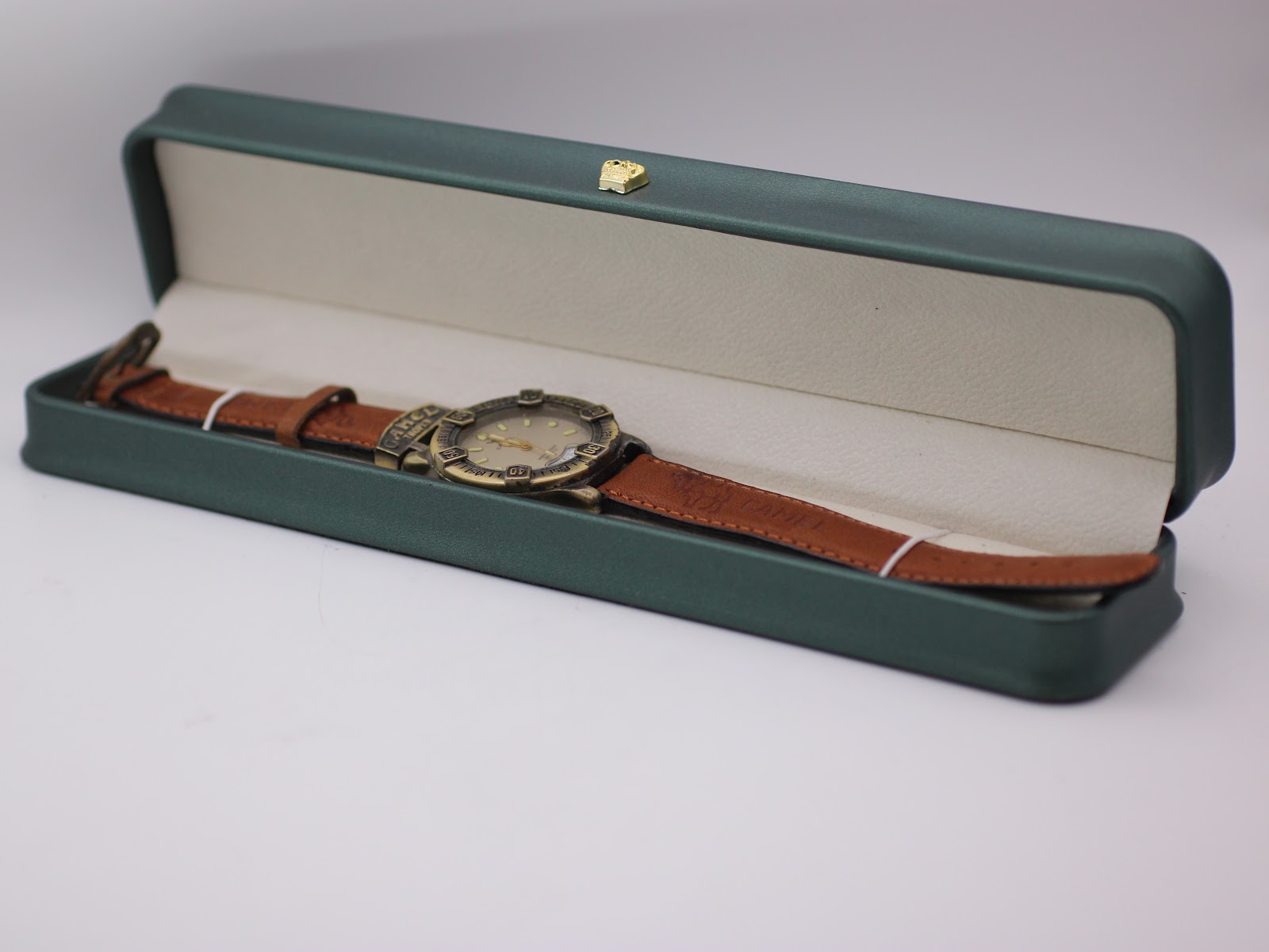 The Camel Trophy watch resting inside a generic green leatherette display box with a small gold crown emblem, against a white background.