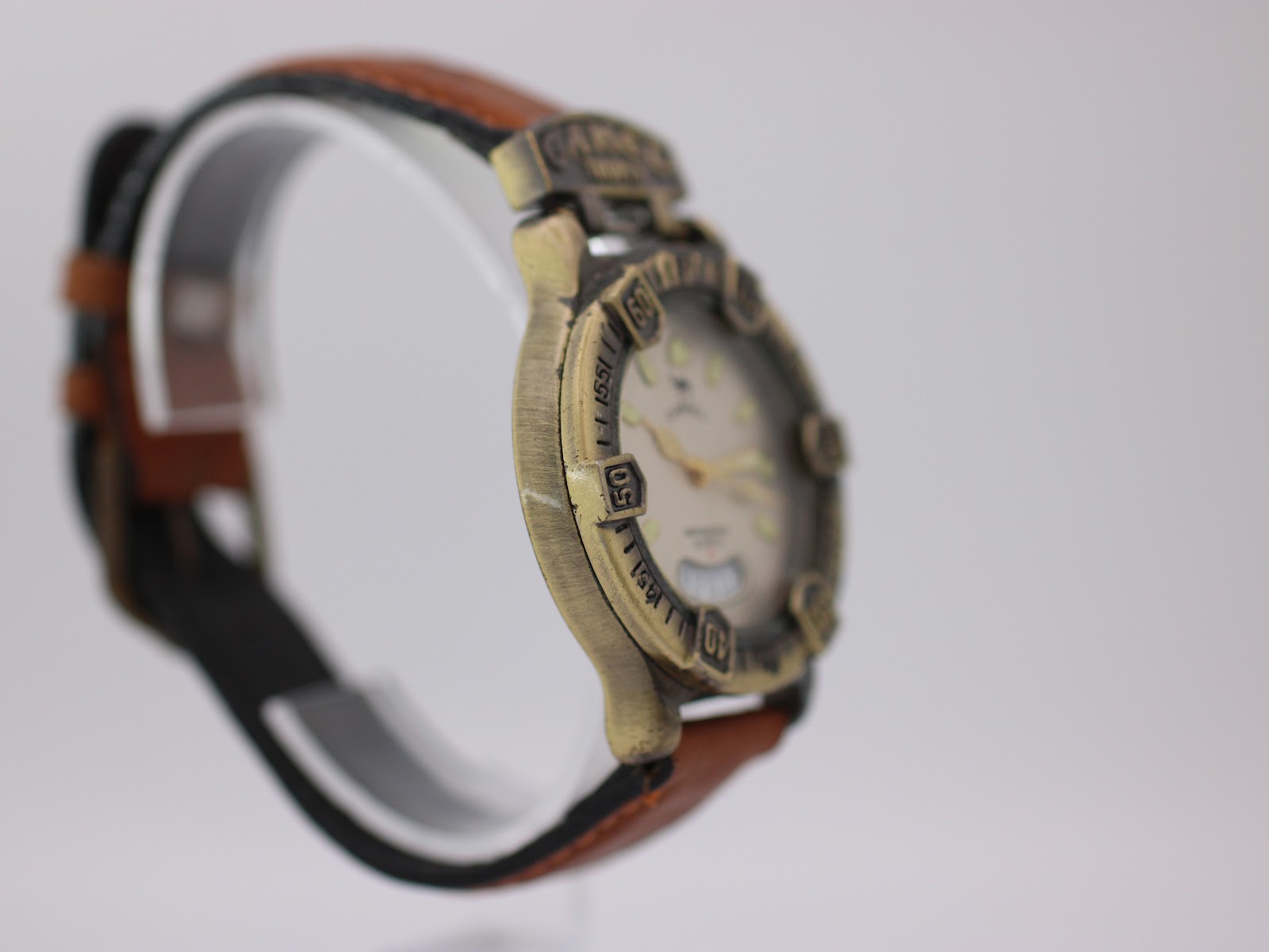 Opposite angled side view of the Camel Trophy watch on a clear stand, showing the case profile and strap attachment.