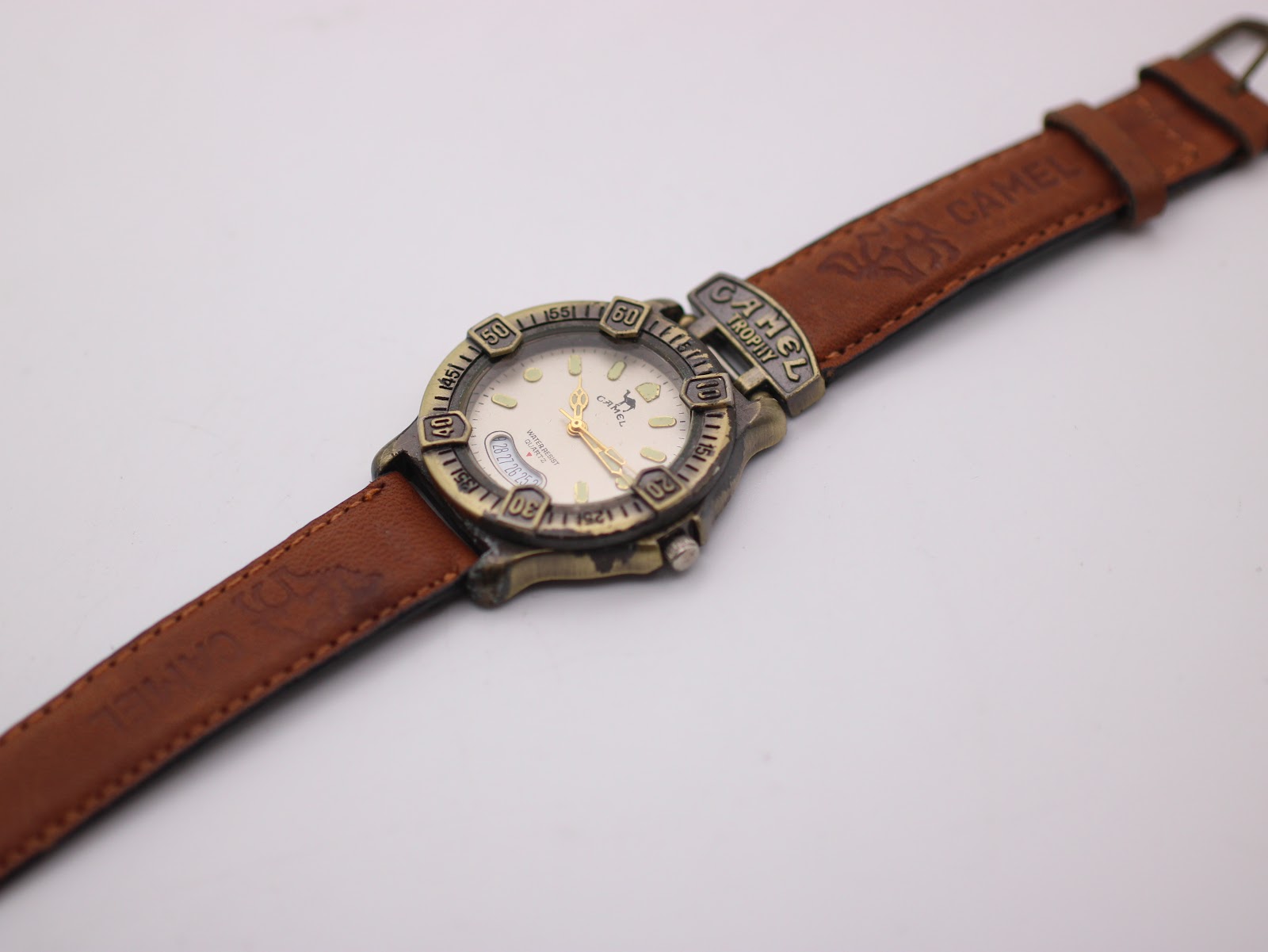 Overhead view of the Camel Trophy watch with its brown leather strap laid flat and extended on a white surface.