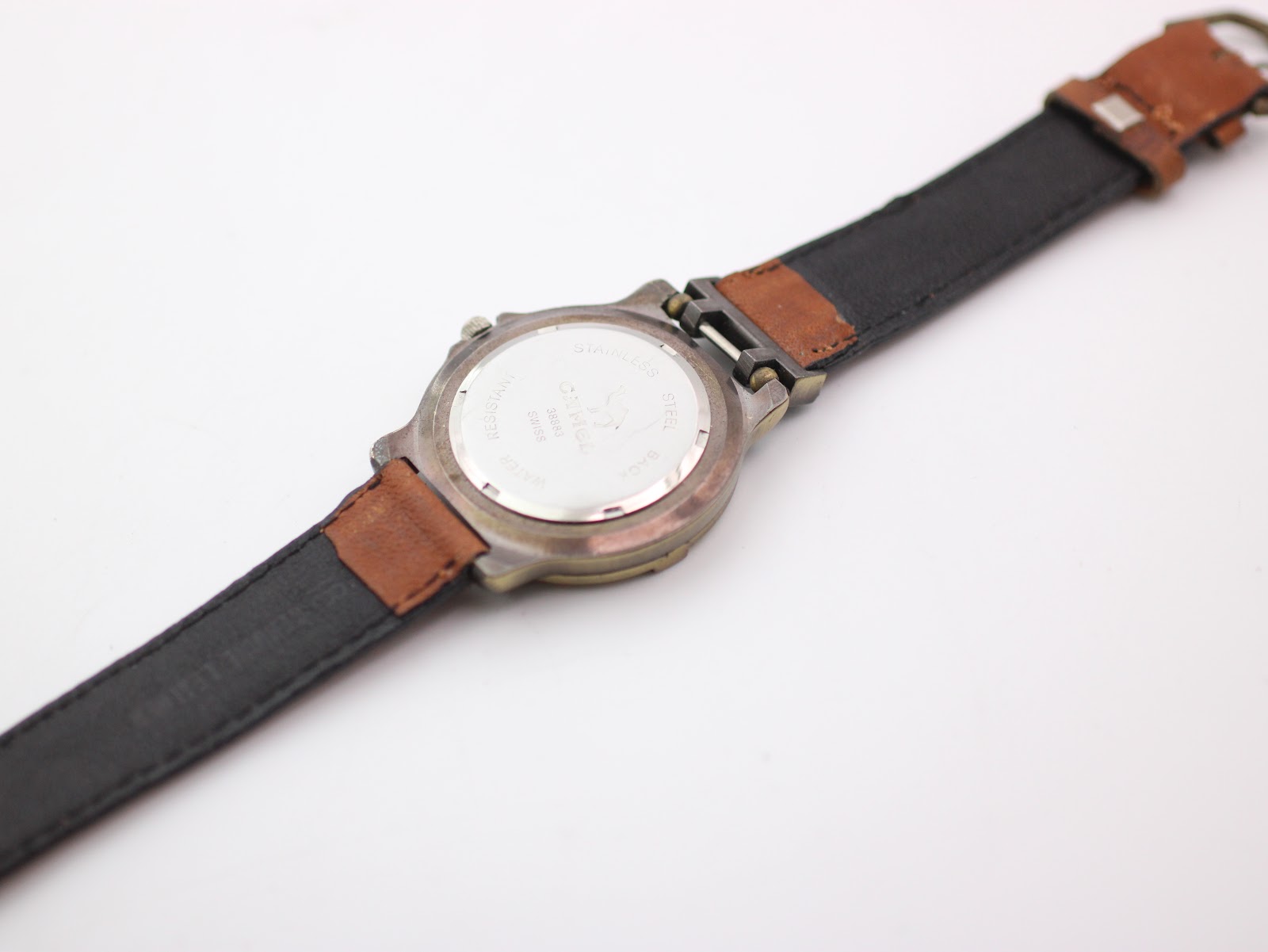 View of the watch's stainless steel case back and the extended brown leather strap, showing its underside.