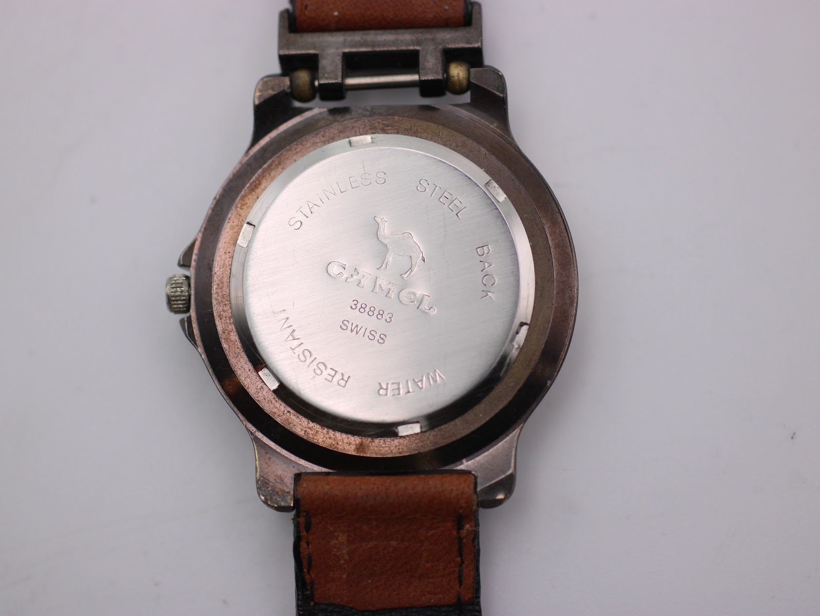 Detailed close-up of the stainless steel case back, engraved with 'CAMEL', 'TROPHY', serial number '38883', 'SWISS', and 'WATER RESISTANT'.