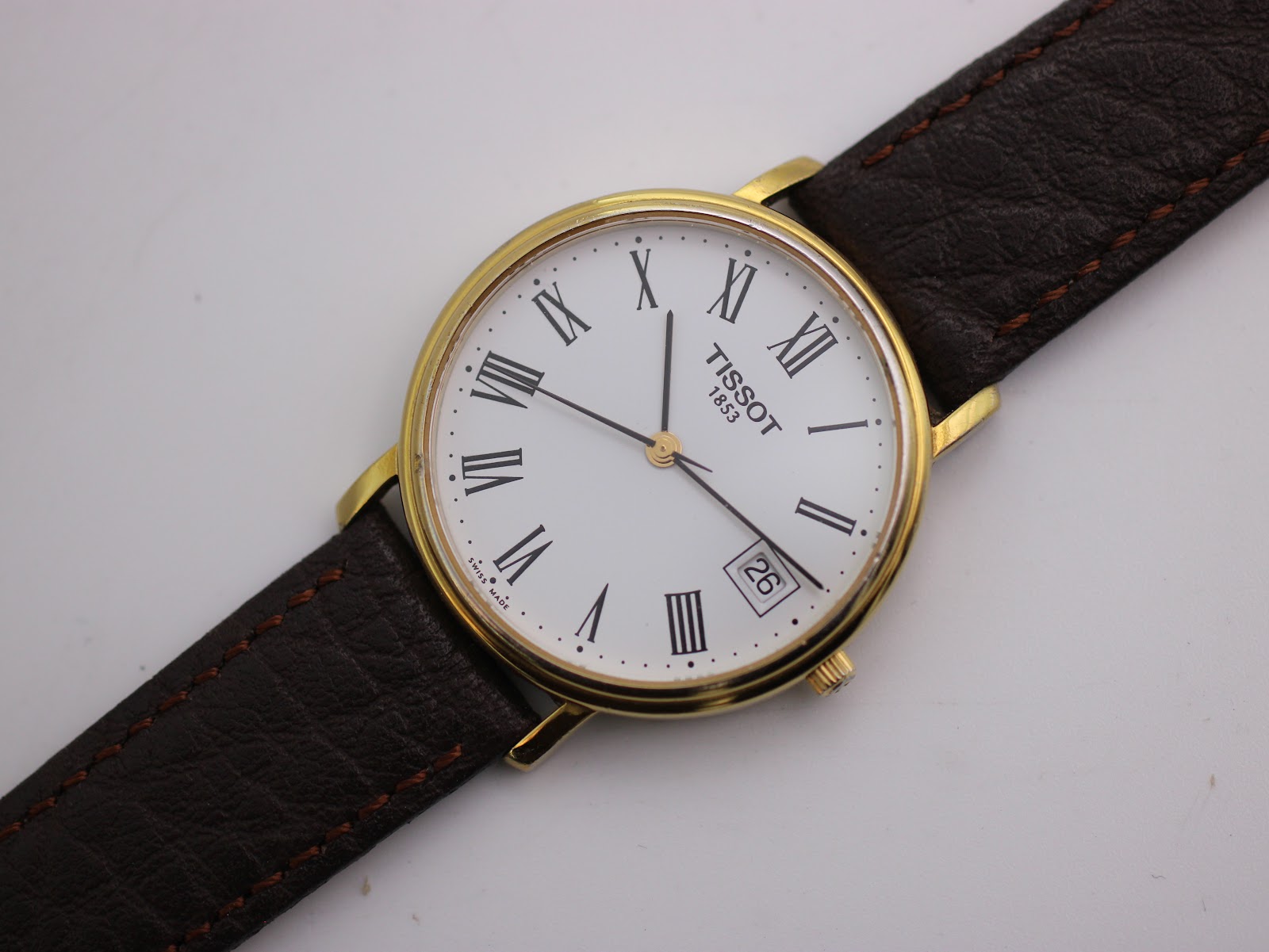 Close-up front view of the Tissot dial, highlighting Roman numerals, date window, and 'TISSOT 1853' branding.