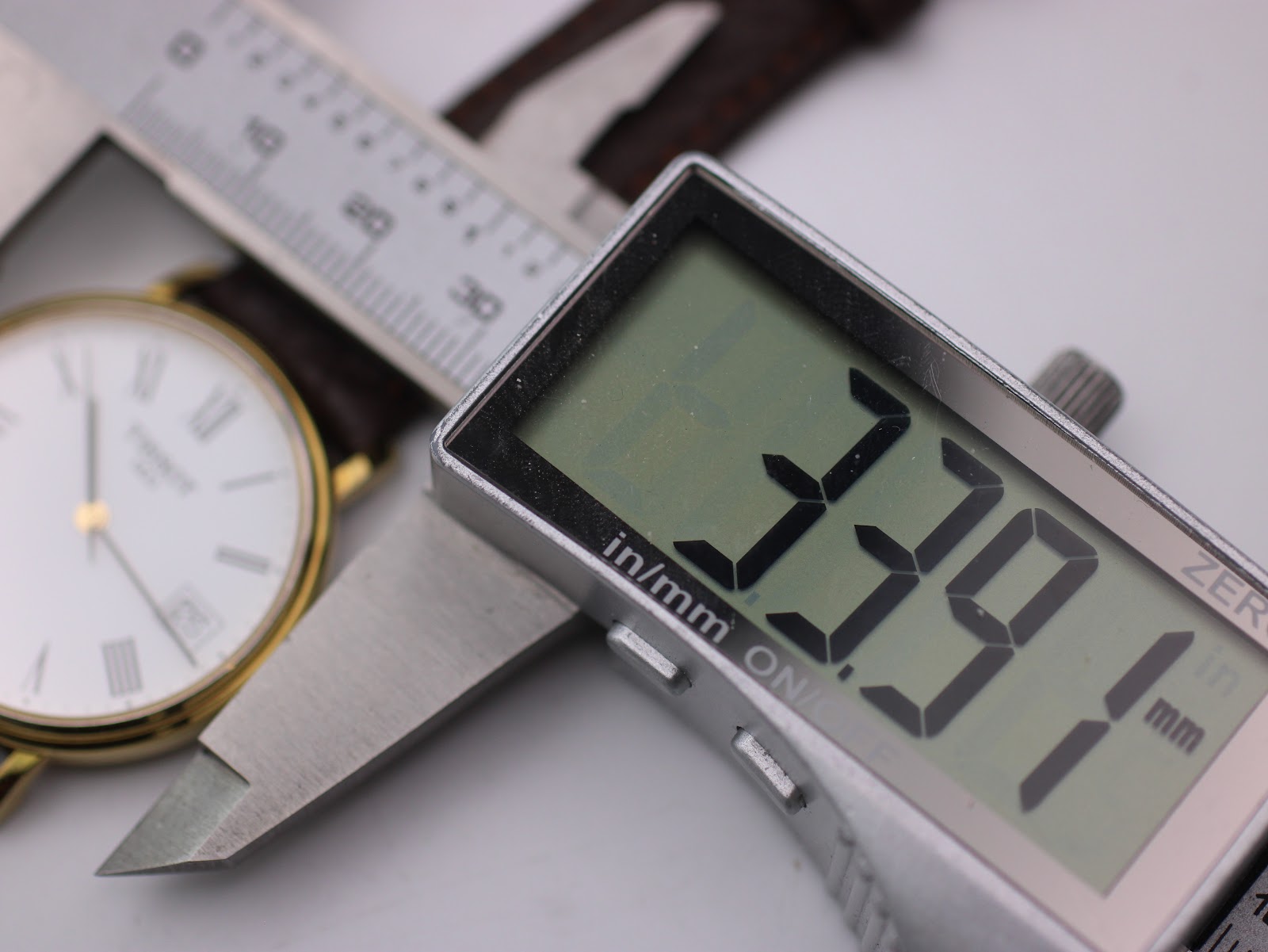 Digital caliper measuring the watch case, displaying a precise diameter of 33.91mm.