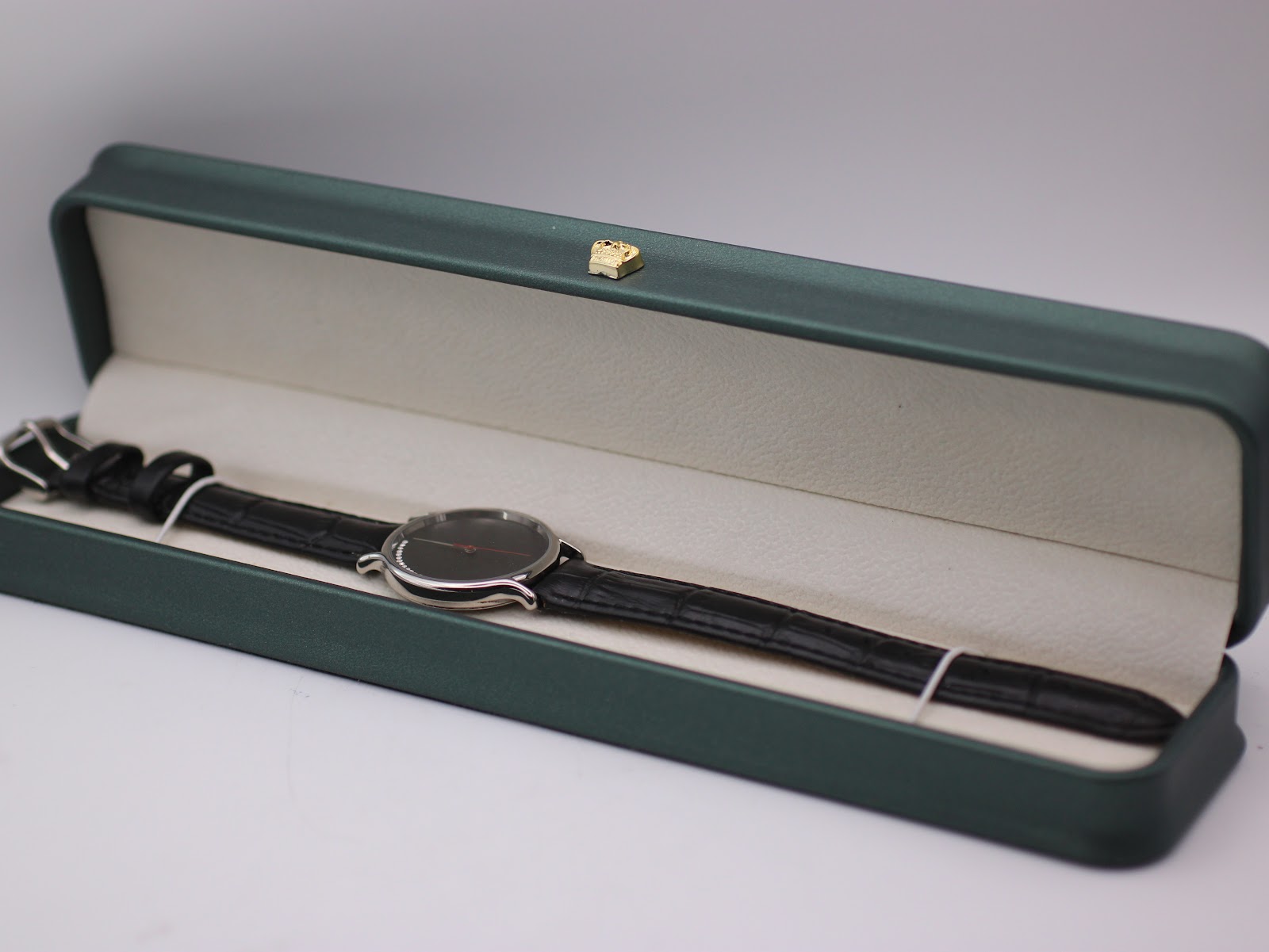 The Michel Jordi watch presented inside a generic green leatherette display box.