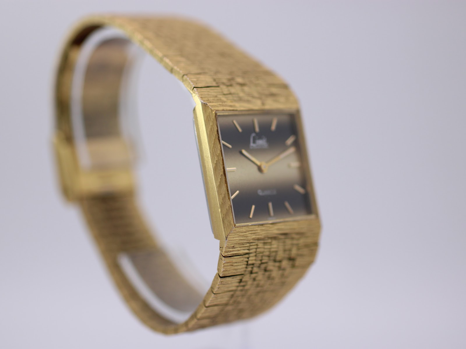 Angled side view showing the gold bark textured integrated bracelet and slim case profile.