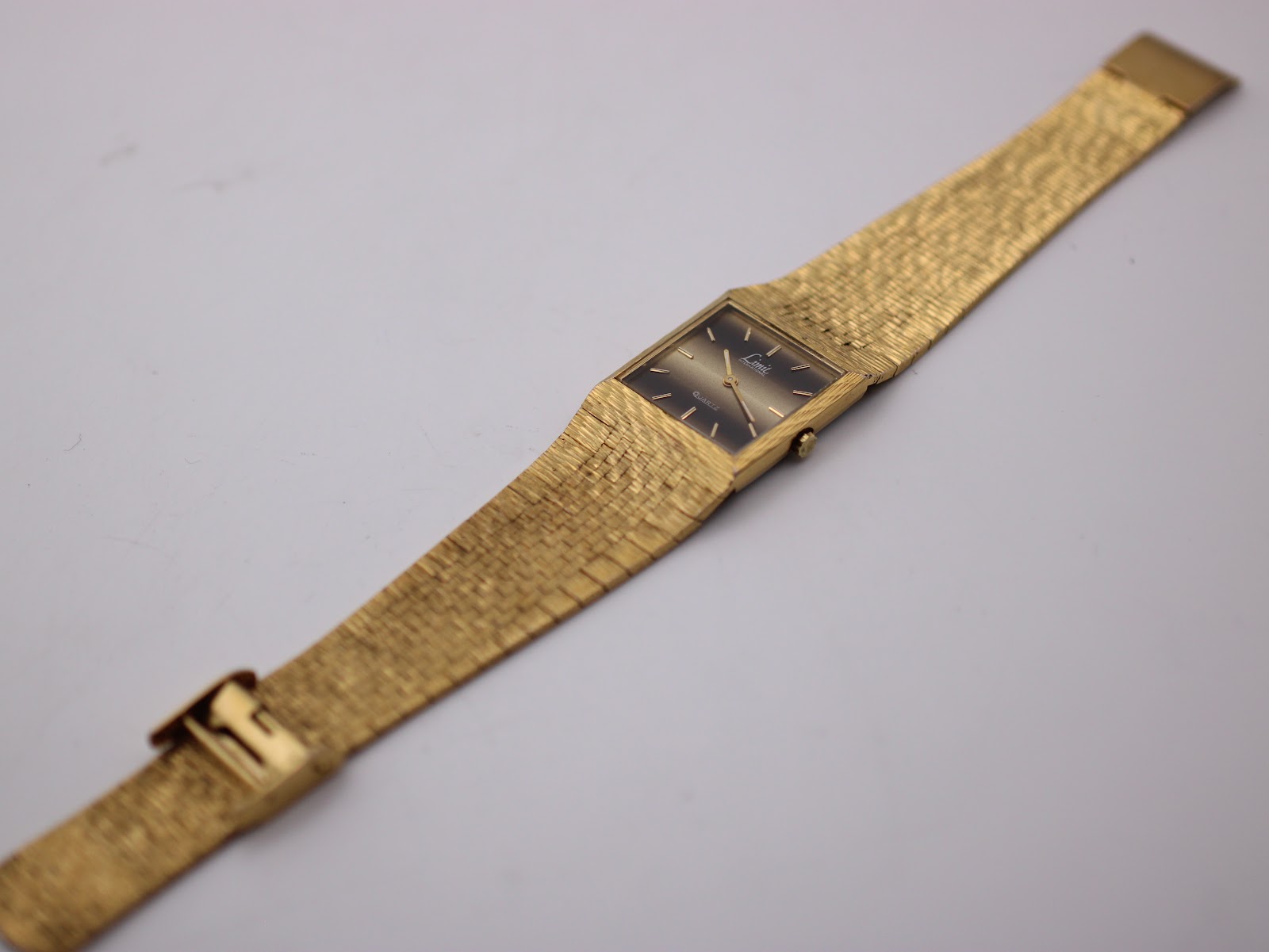 Side view of the vintage Limit International watch on a stand.