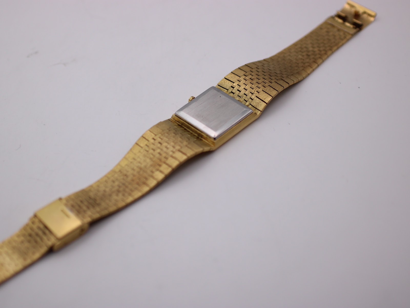 Overhead view of the gold watch laid flat, displaying the integrated bark textured bracelet and clasp.