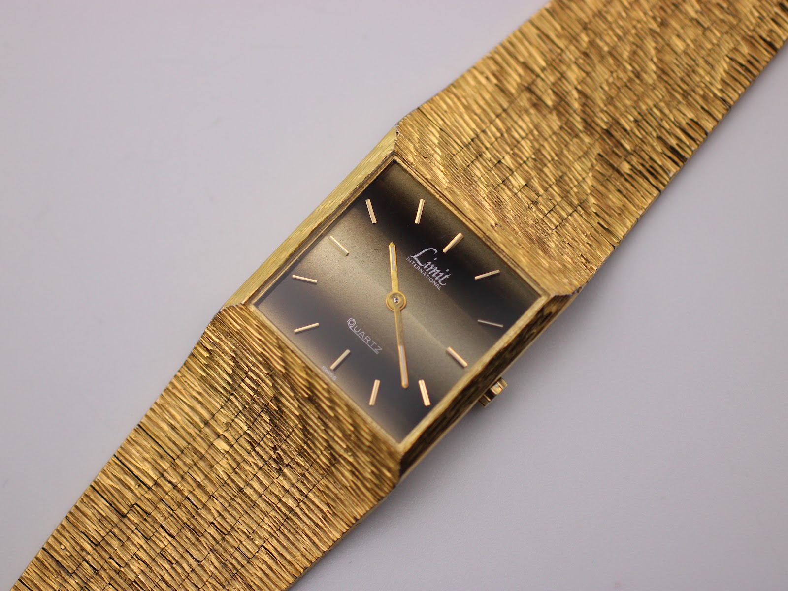 View of the brushed stainless steel case back and the reverse of the gold textured bracelet.
