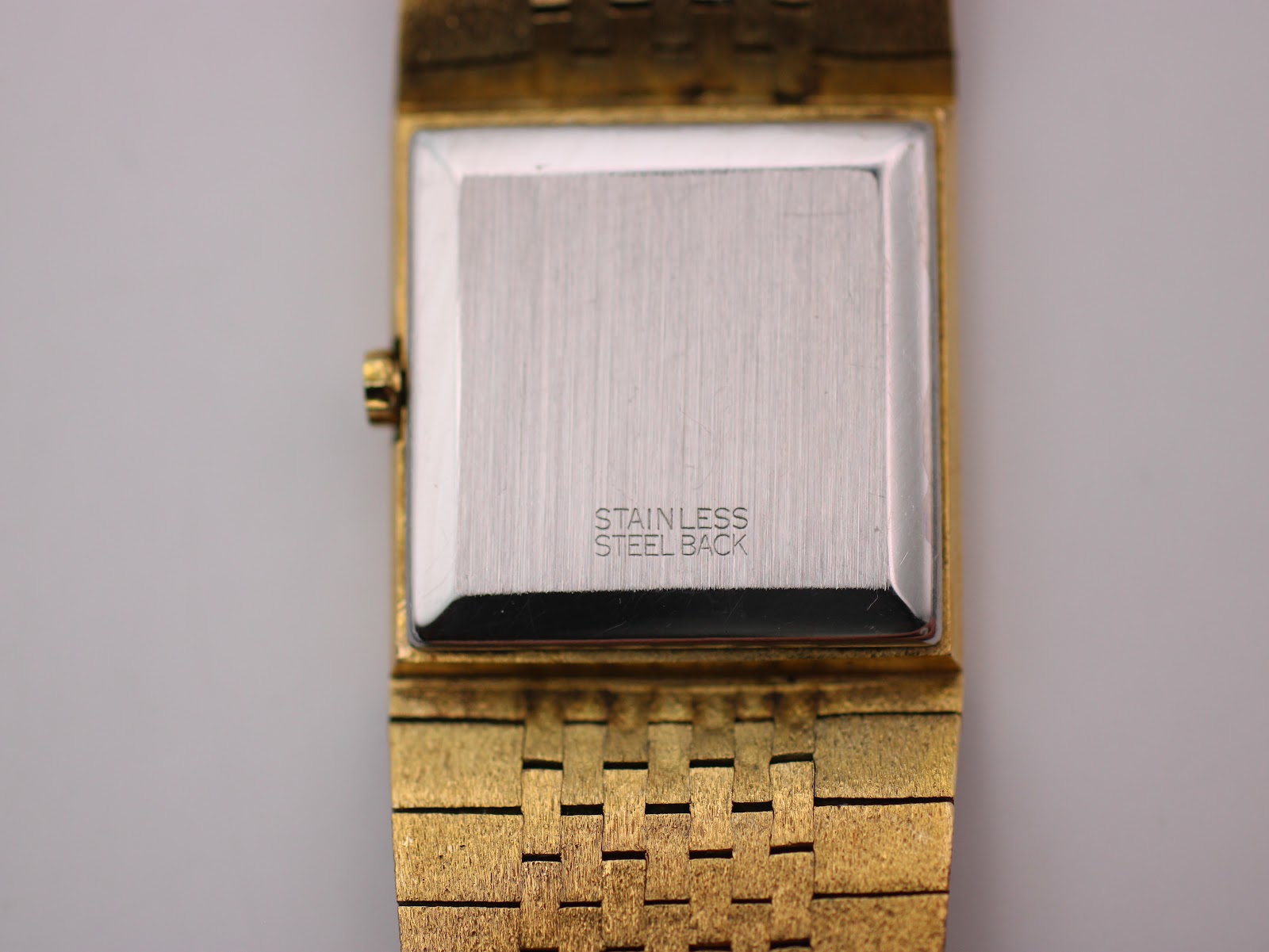Close-up front view highlighting the ombre tiger eye dial, gold baton indices, and bark texture.