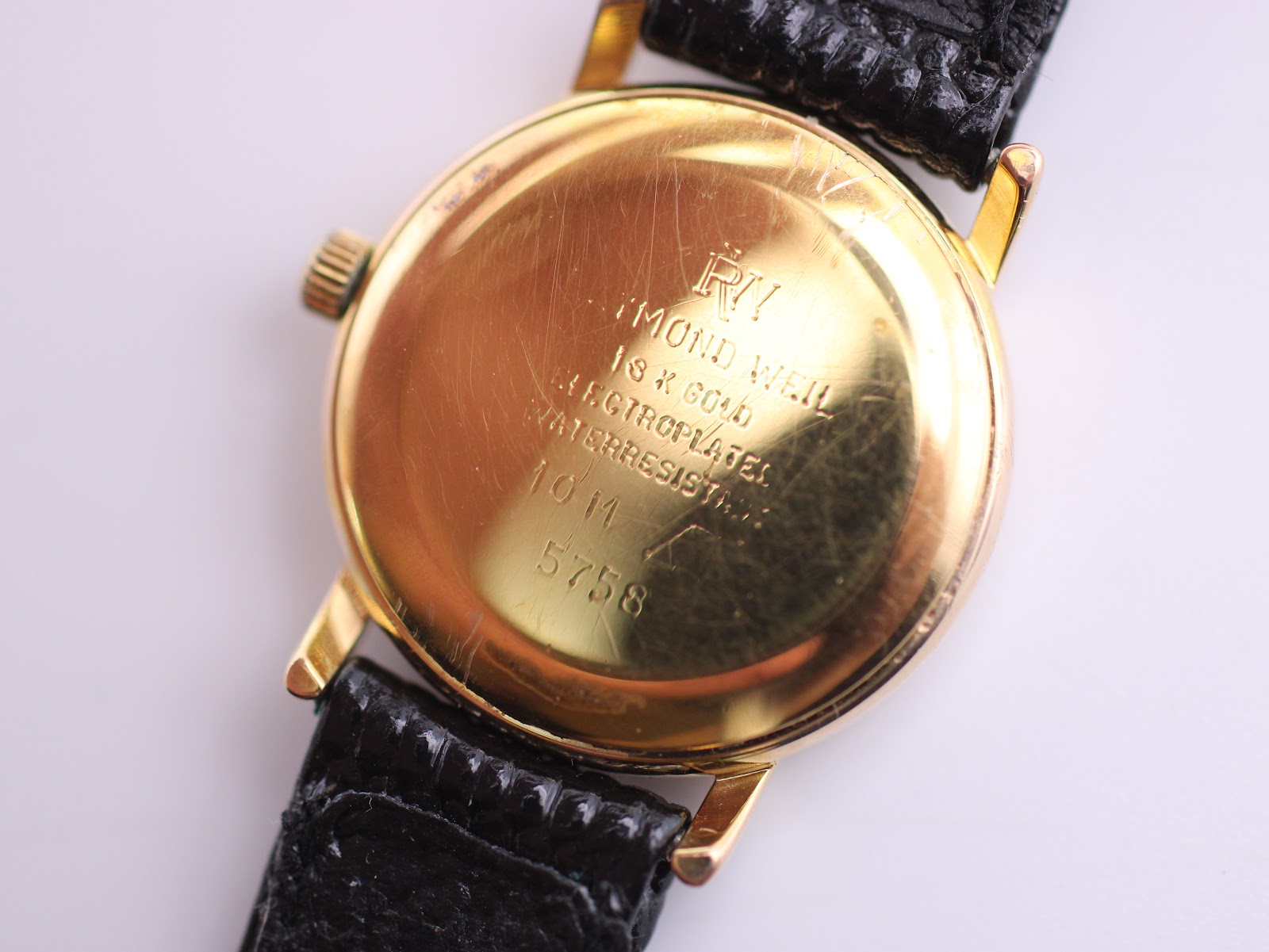 Close-up of the Raymond Weil gold case back with engravings "RAYMOND WEIL", "18 K GOLD ELECTROPLATED", "WATERRESISTANT 10 M", and "5758".