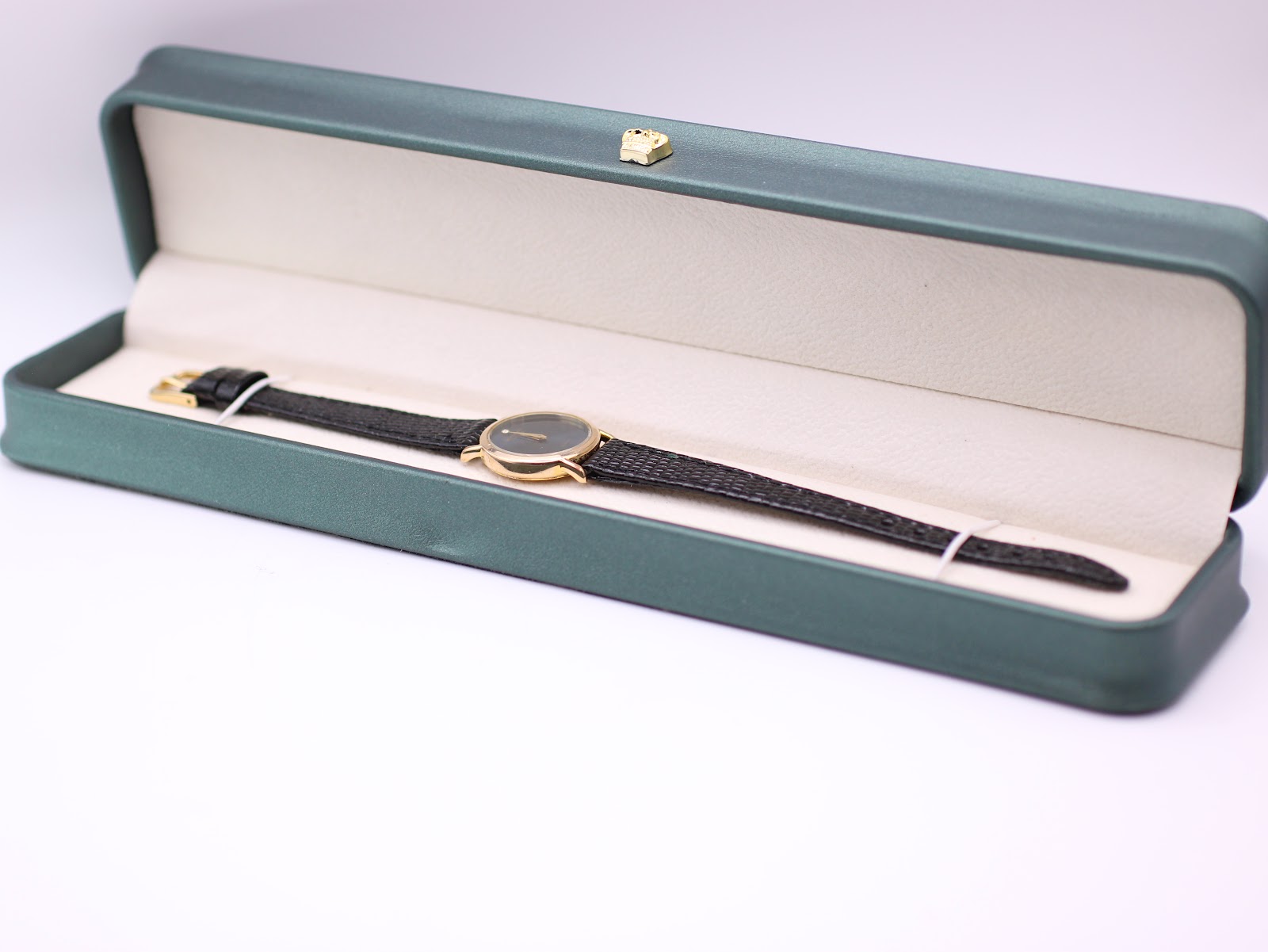 Raymond Weil watch inside a green leatherette display box, showing the full watch and strap.