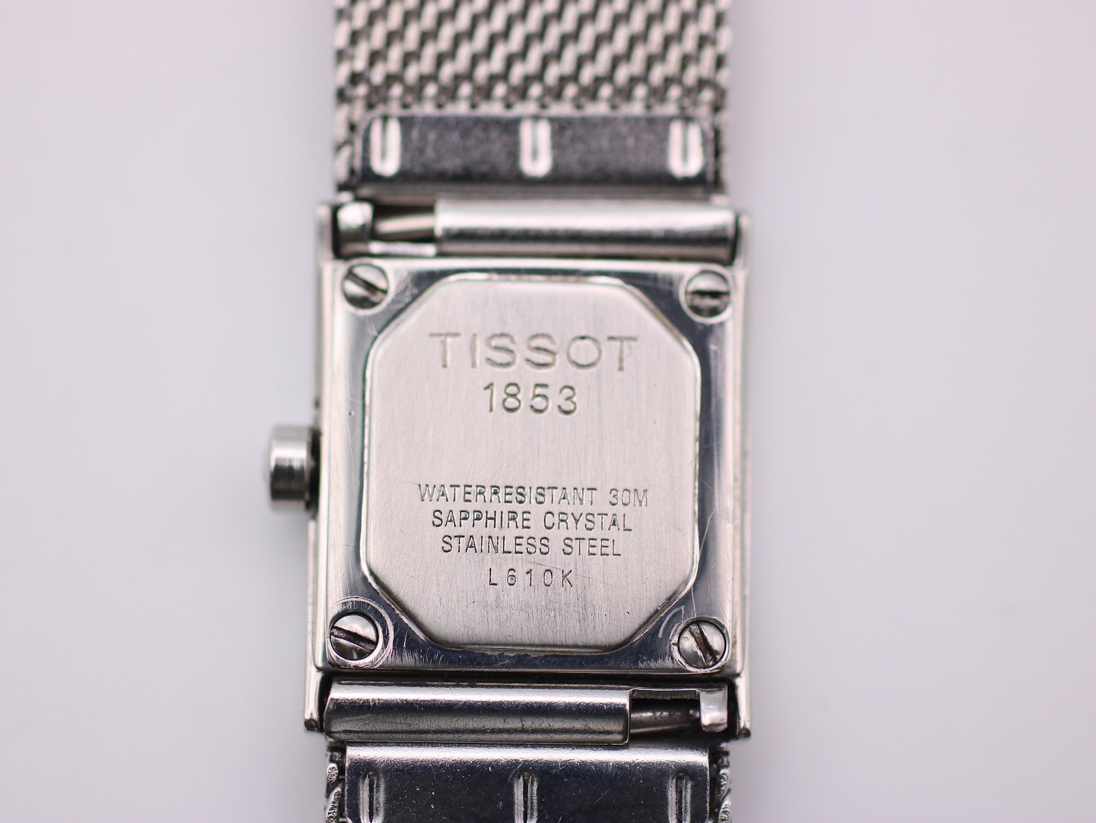Close-up of the Tissot L610K case back, clearly showing engravings: 'TISSOT 1853', 'WATERRESISTANT 30M', 'SAPPHIRE CRYSTAL', 'STAINLESS STEEL', and 'L610K'.