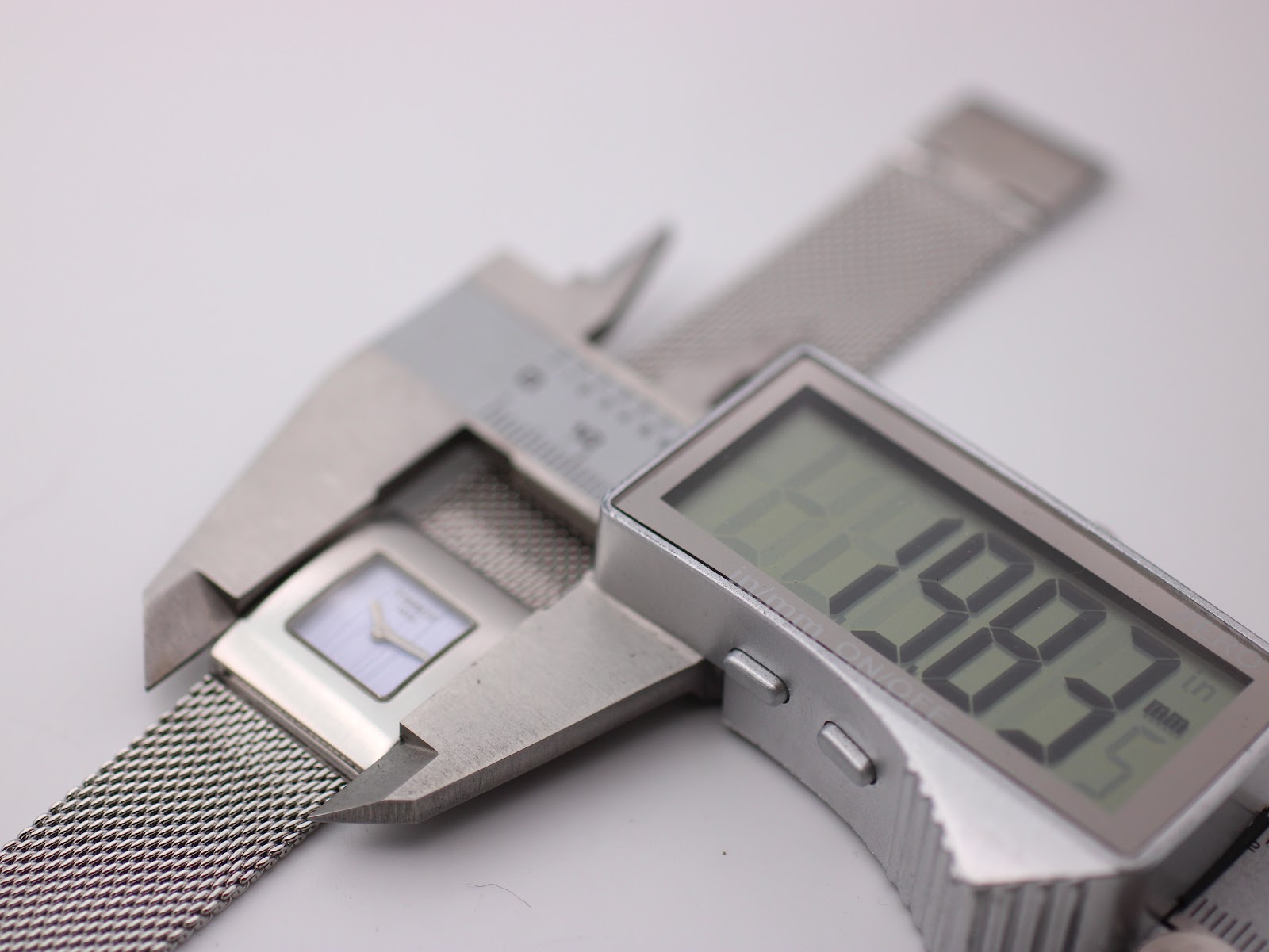 Digital caliper measuring the Tissot L610K watch case, displaying a precise measurement of 19.82mm.