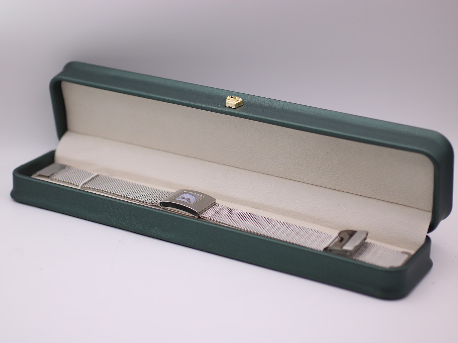 The Tissot L610K watch with its mesh bracelet arranged inside a generic green leatherette presentation box.