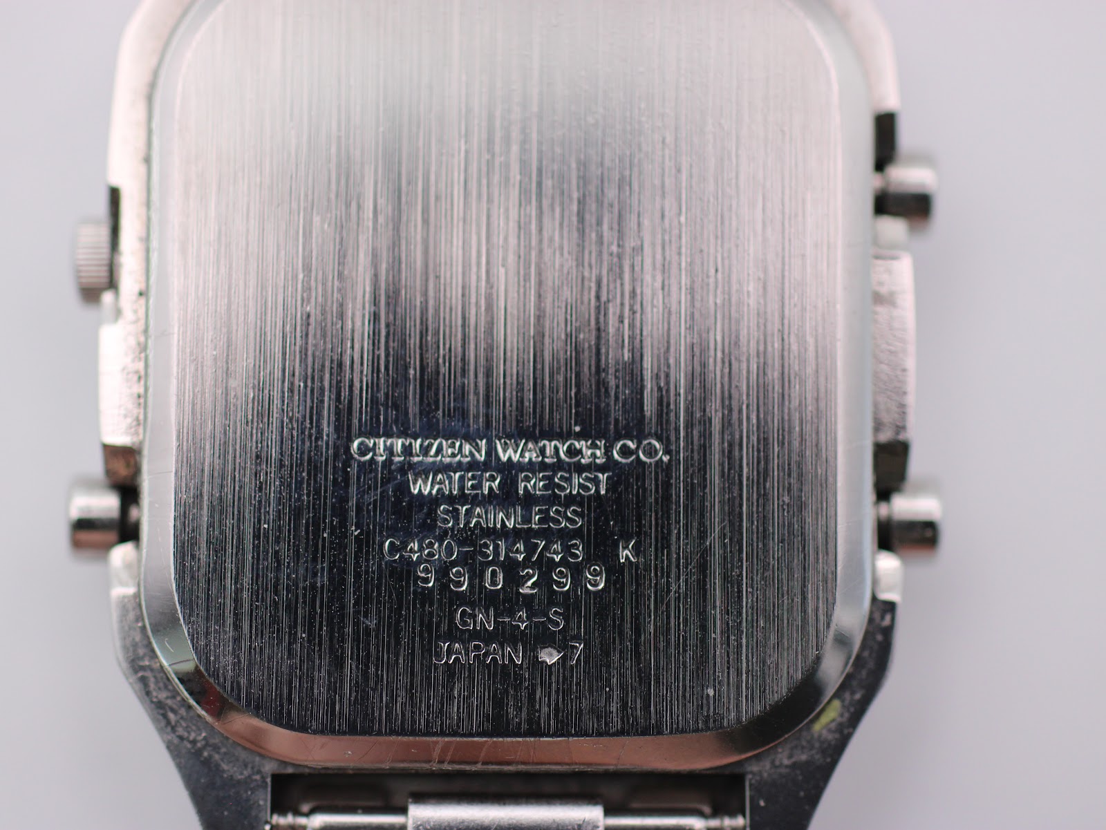 Close-up of the brushed stainless steel case back with "CITIZEN WATCH CO. WATER RESIST STAINLESS C480-314743 K 990299 GN-4-S JAPAN" engravings.