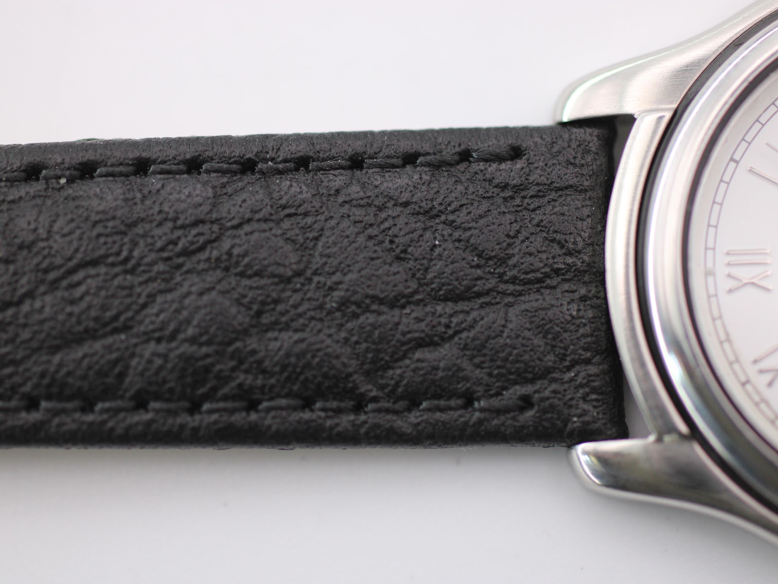 Close-up of the textured black leather strap and its connection to the watch lugs.