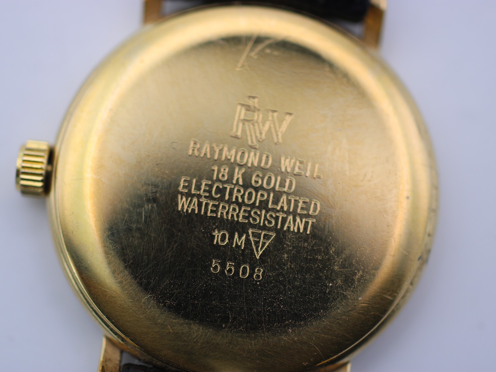 Close-up of the gold-plated case back, engraved with "RAYMOND WEIL 18 K GOLD ELECTROPLATED WATERRESISTANT 10 M" and model "5508".