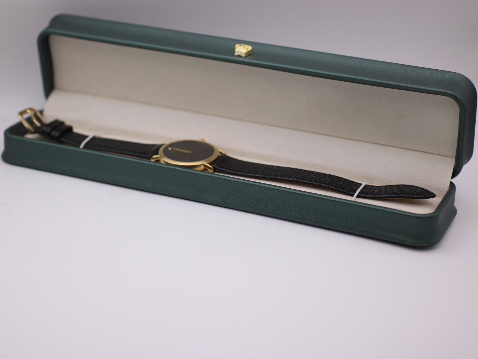 The Raymond Weil watch resting inside a generic green leatherette display box.