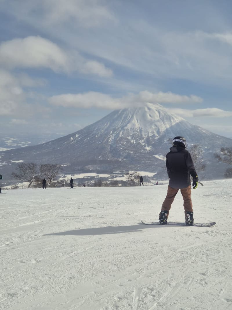Snowboarder en pista con el monte Yotei al fondo, Niseko