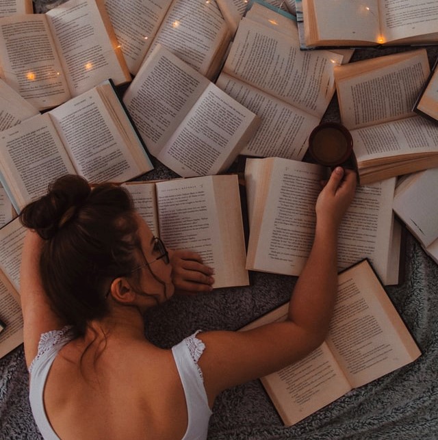 girl lying on pile of books