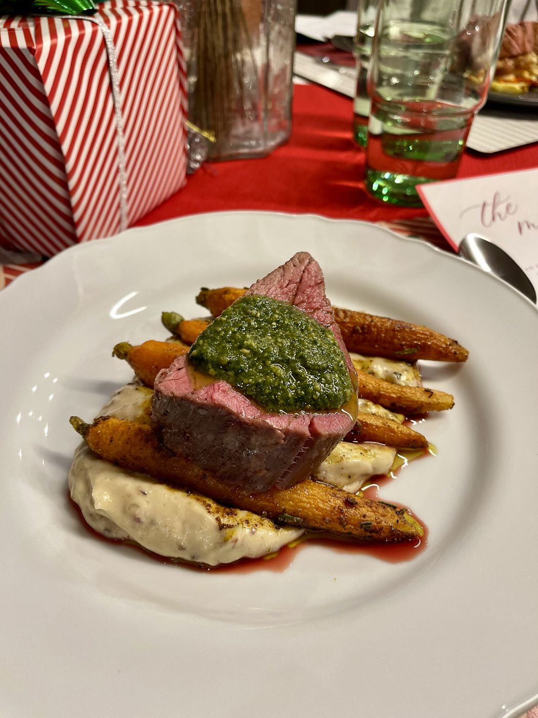 A plated holiday main course with steak, carrots and chimichurri