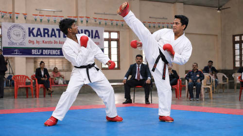 Two karate practitioners engaged in a sparring exchange during kumite