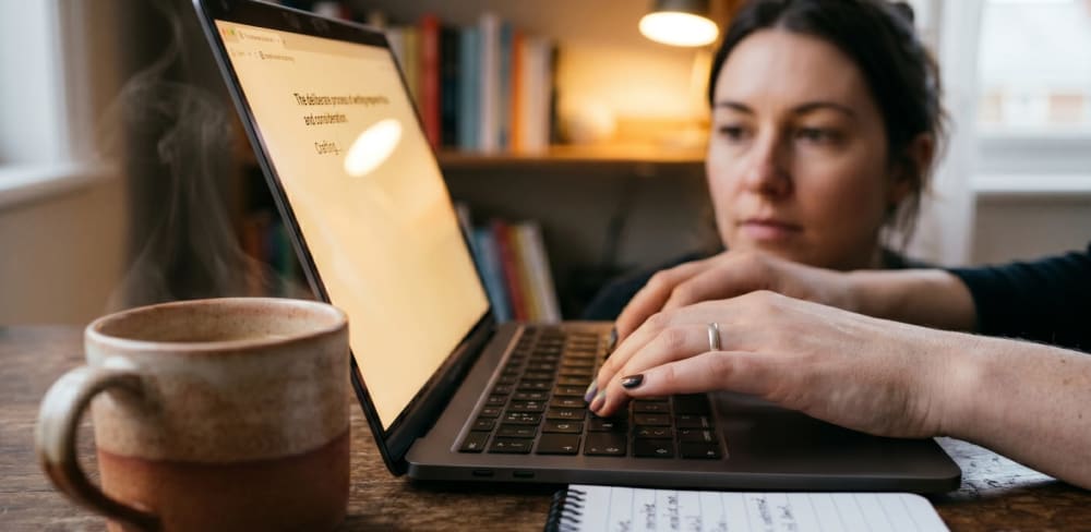 Hôte Airbnb analysant les avis voyageurs sur un dashboard, stylo à la main, carnet de notes ouvert