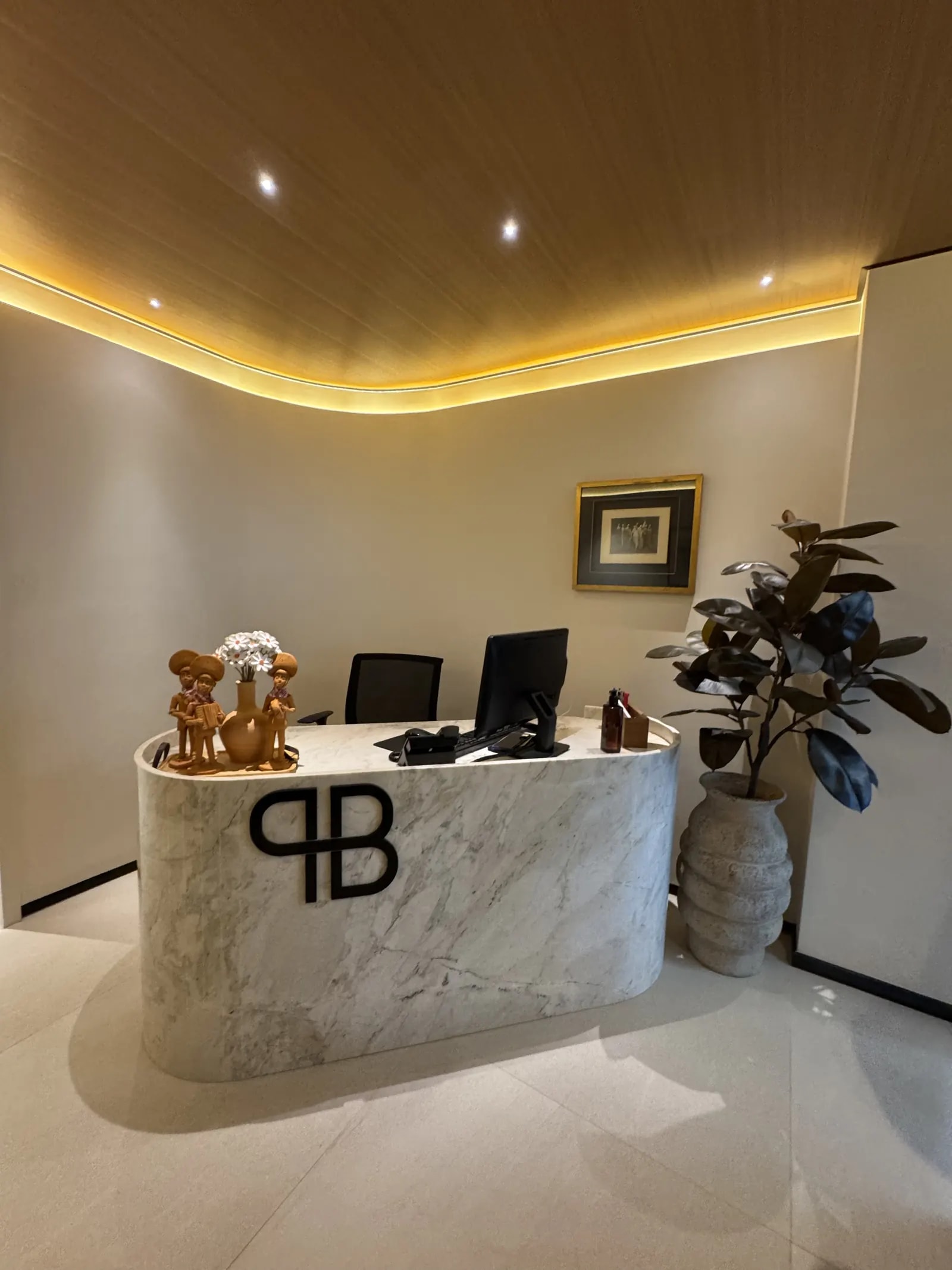 Recepção da Clínica Paula Barreto, com balcão de mármore e o monograma PB