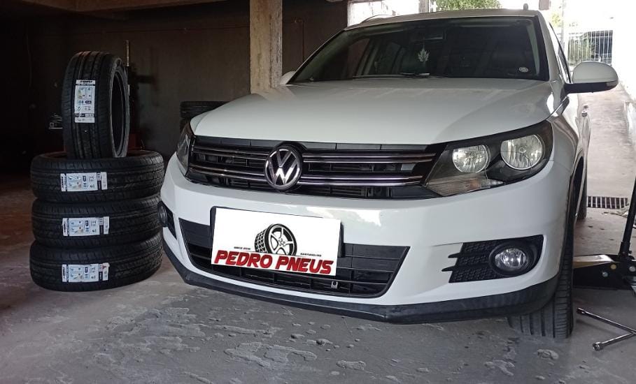 Carro atendido ao lado de pneus novos na loja
