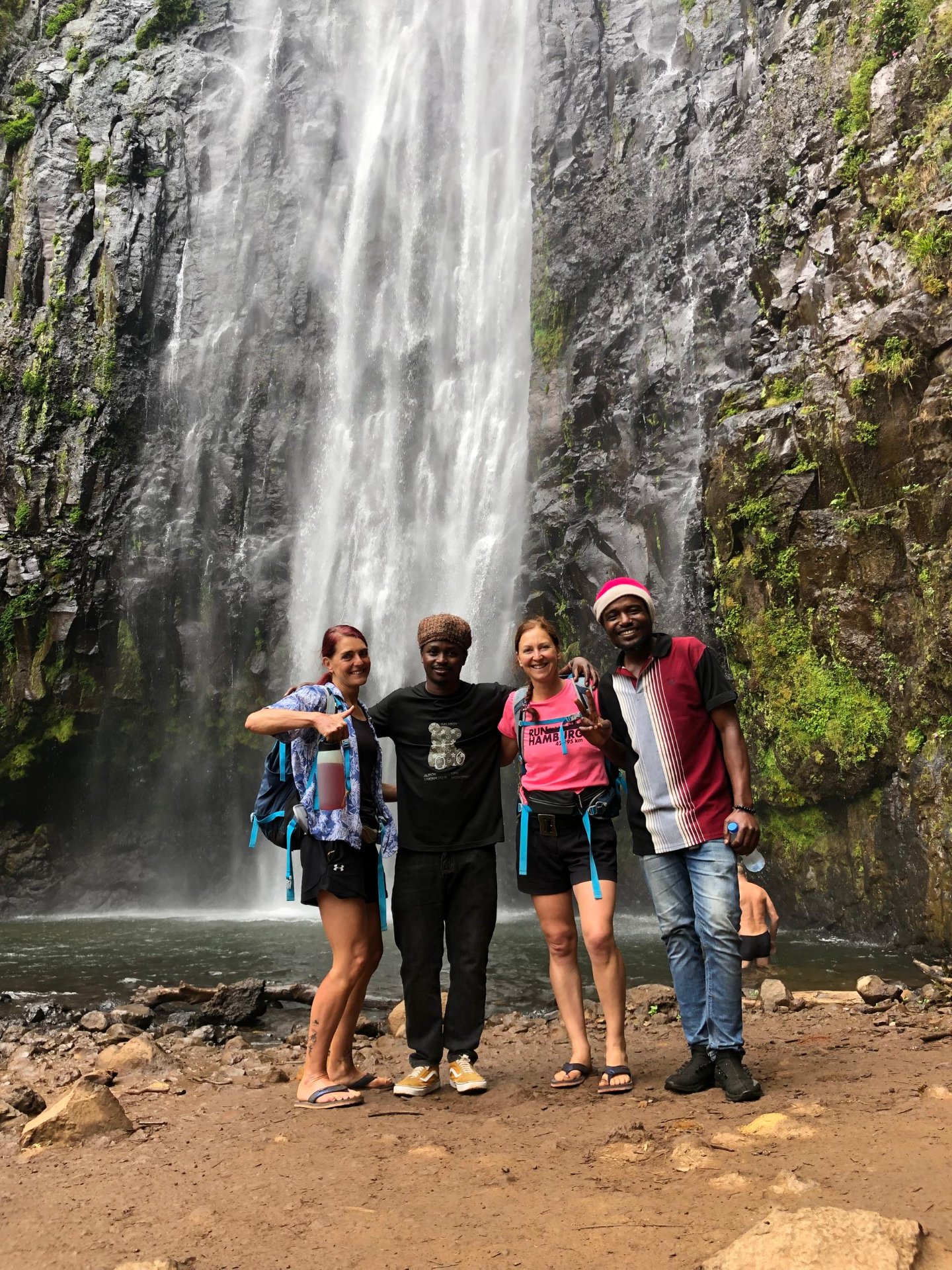 Visitors hiking to Materuni Waterfalls through lush rainforest near Moshi