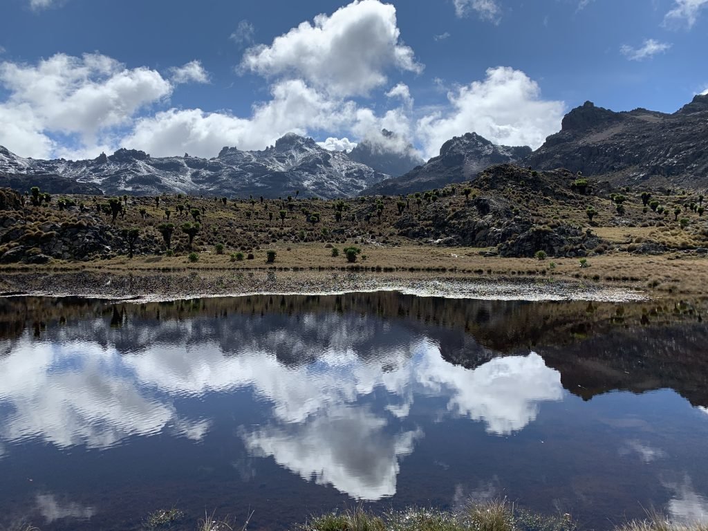 Turquoise alpine lake surrounded by rocky peaks and snow patches on Mount Kenya