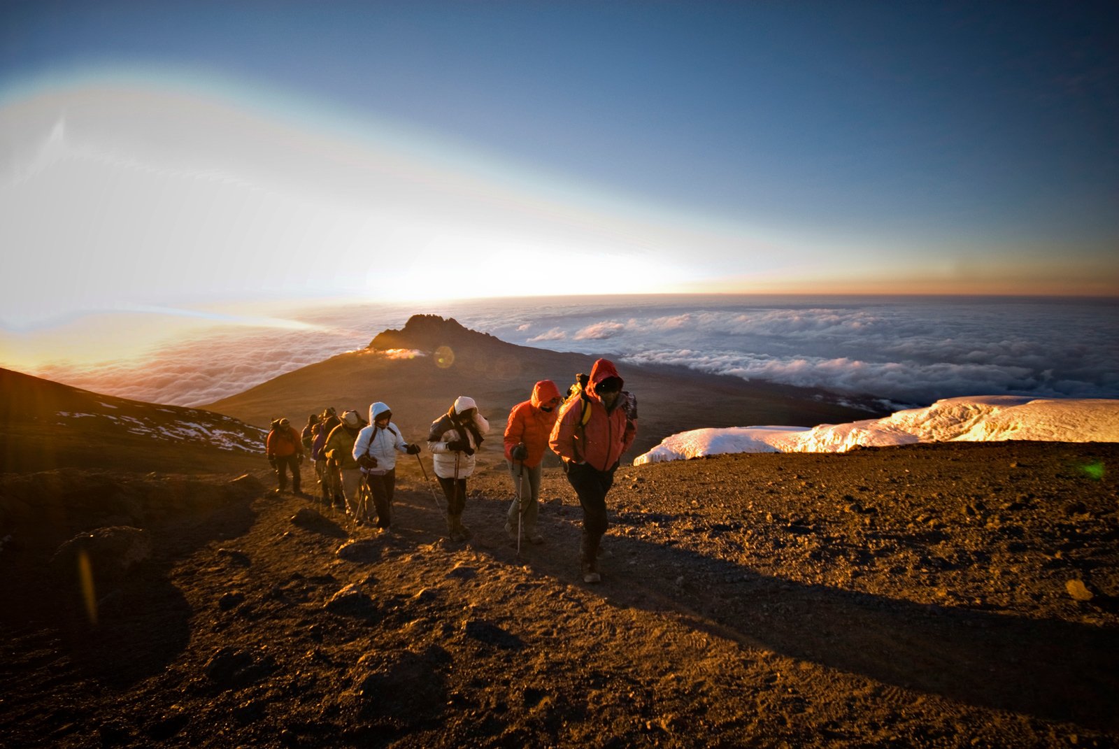 Group of climbers celebrating at Uhuru Peak sunrise summit on Kilimanjaro