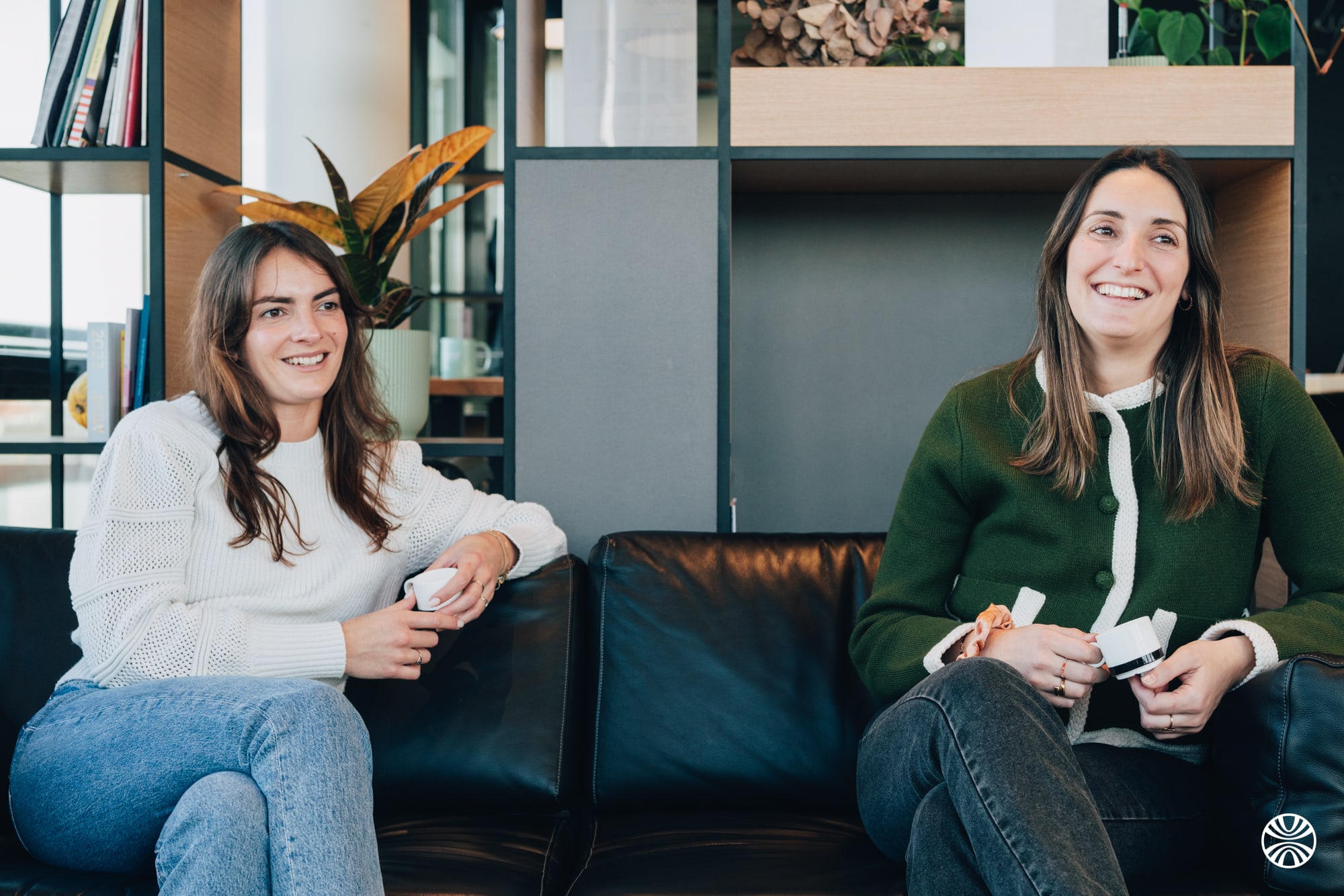 Finthesis team members sitting on a couch, talking and laughing
