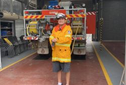 Person behind fire truck holding hose wearing firefighter clothing